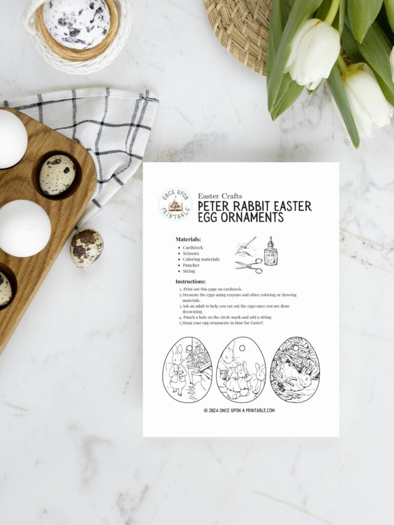 The tale of Peter Rabbit ornament directions laying on a marble top with eggs and tulips.