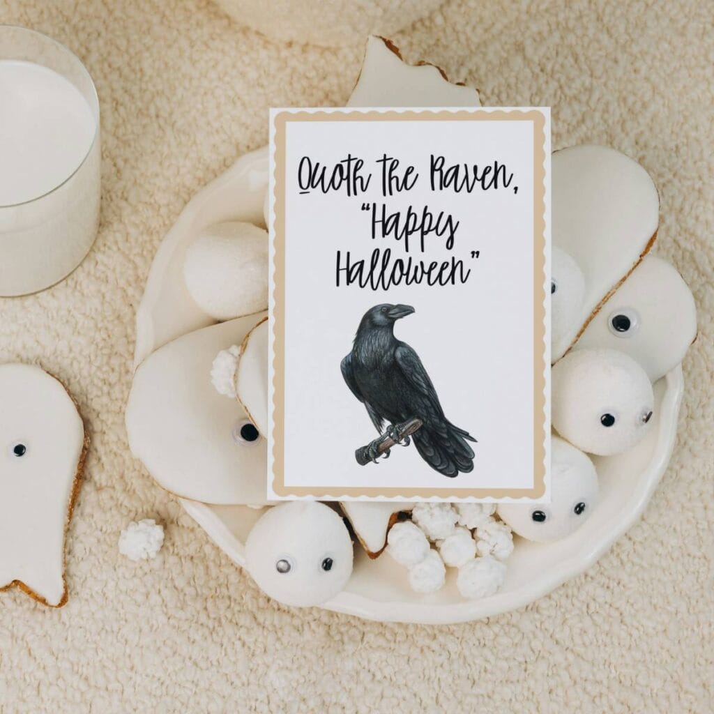 A Raven on a Halloween notecard sitting on top of a pile of ghost cookies iced with white icing.