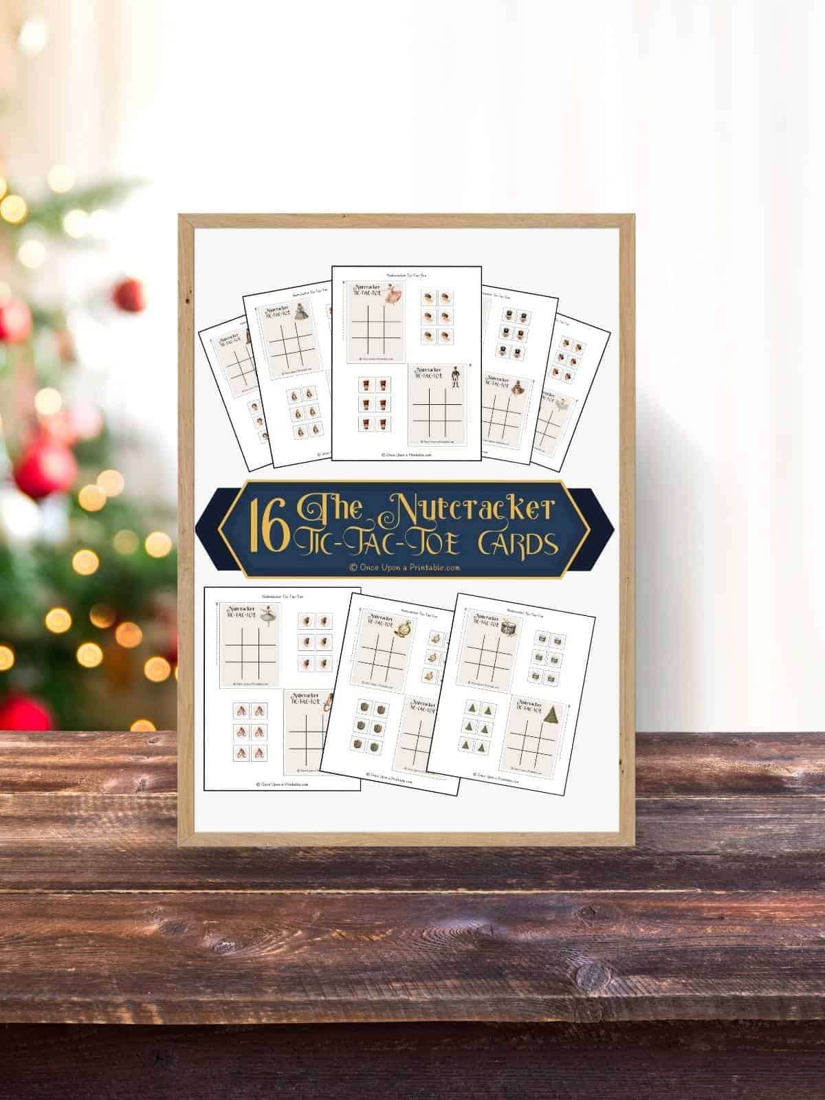 The cover page of the Nutcracker themed tic tac toe cards on a wooden surface with a christmas tree in the background.