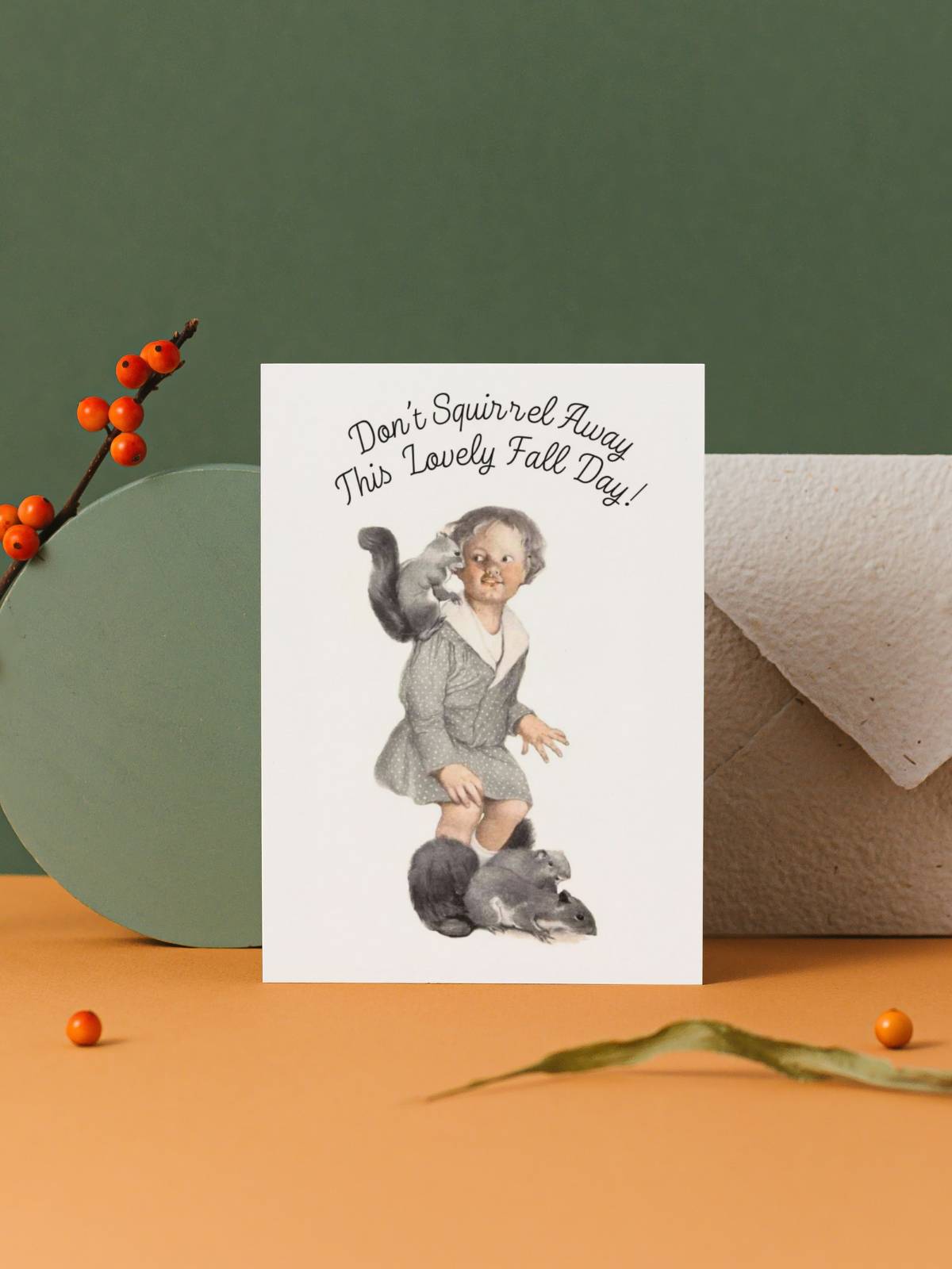 Little girl with squirrels, illustrated by Sarah Stilwell-Weber, greeting card displayed with an envelope by berries on a twig and dried leaves.
