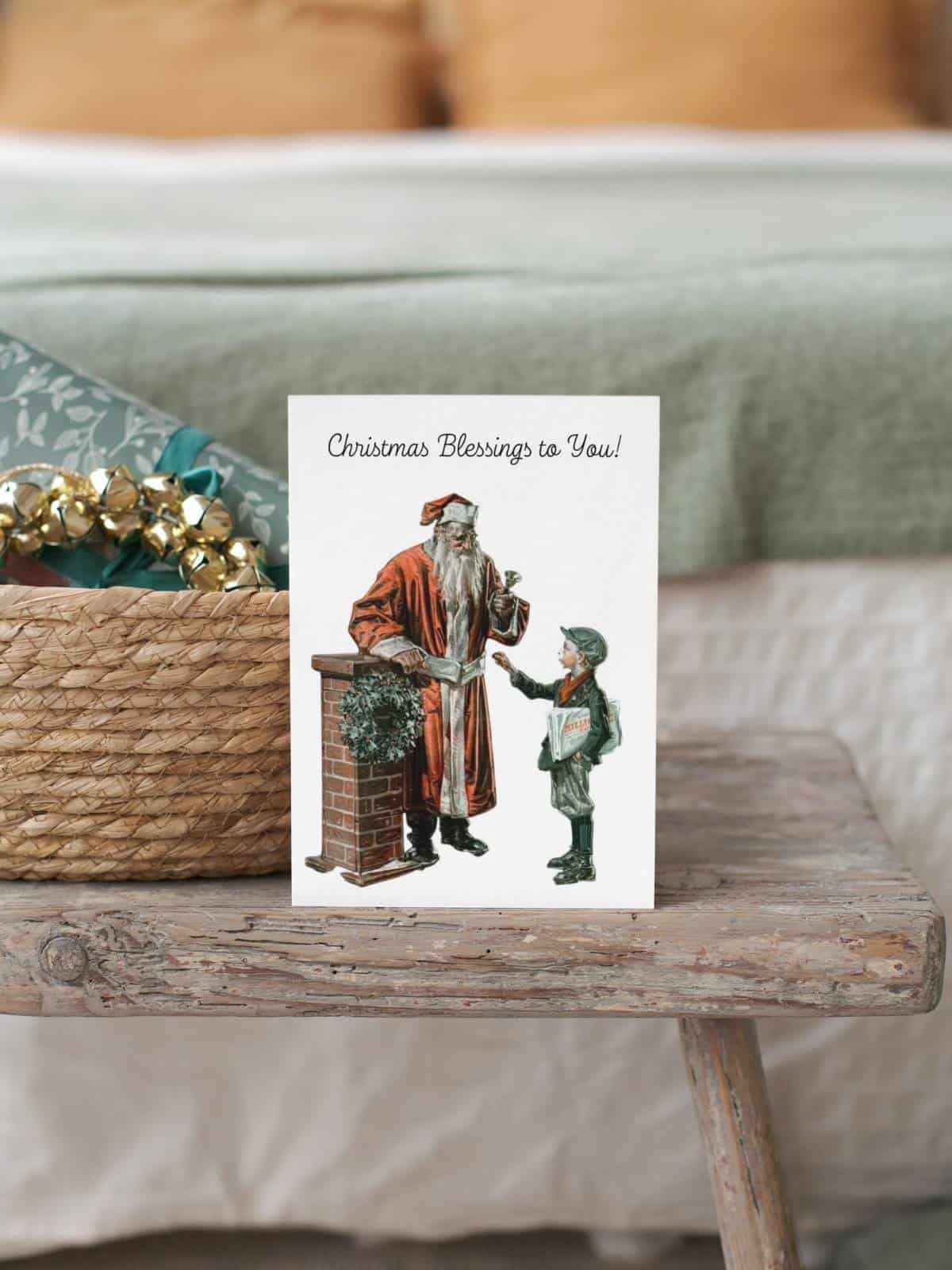 Santa Claus ringing a bell for charity and a little boy giving him a coin for the bucket. A greeting card sitting on a wooden bench by a table.