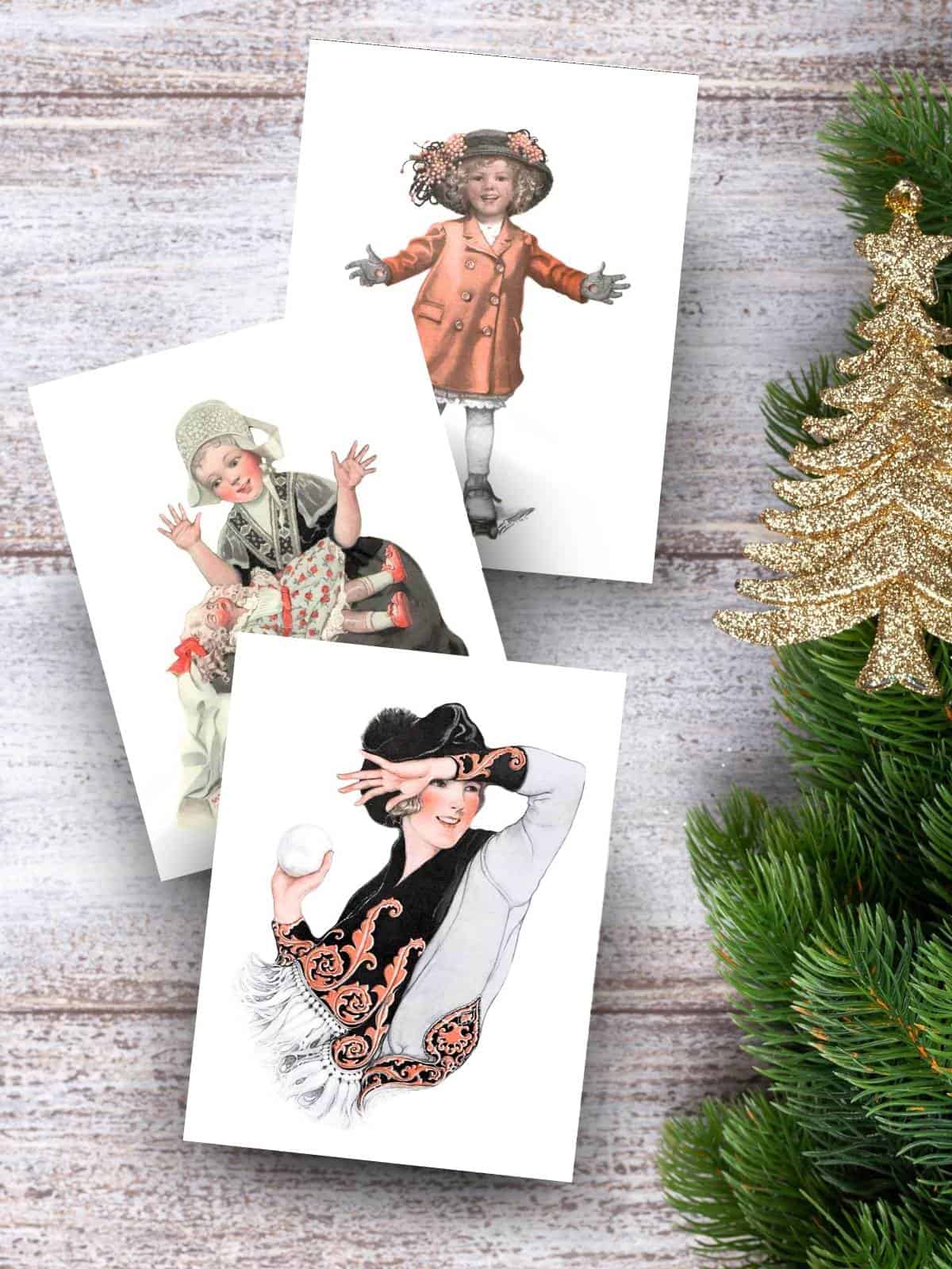 Winter illustrations by artist Sarah Stilwell Weber sitting on a wooden table next to a christmas tree and a golden tree ornament.