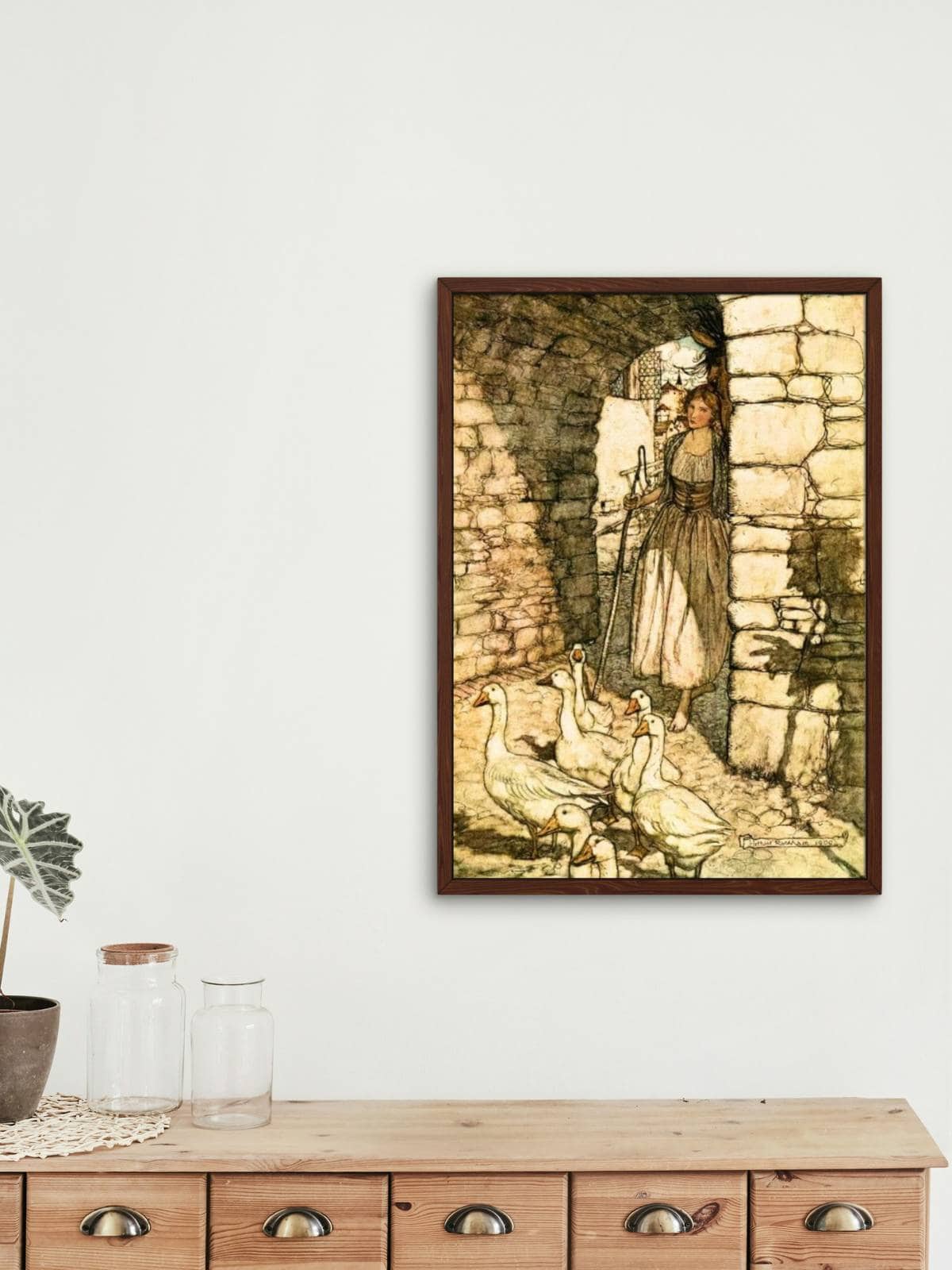 The Goose Girl illustration by Arthur Rackham framed and displayed on a wall above a vintage wooden cabinet with drawers