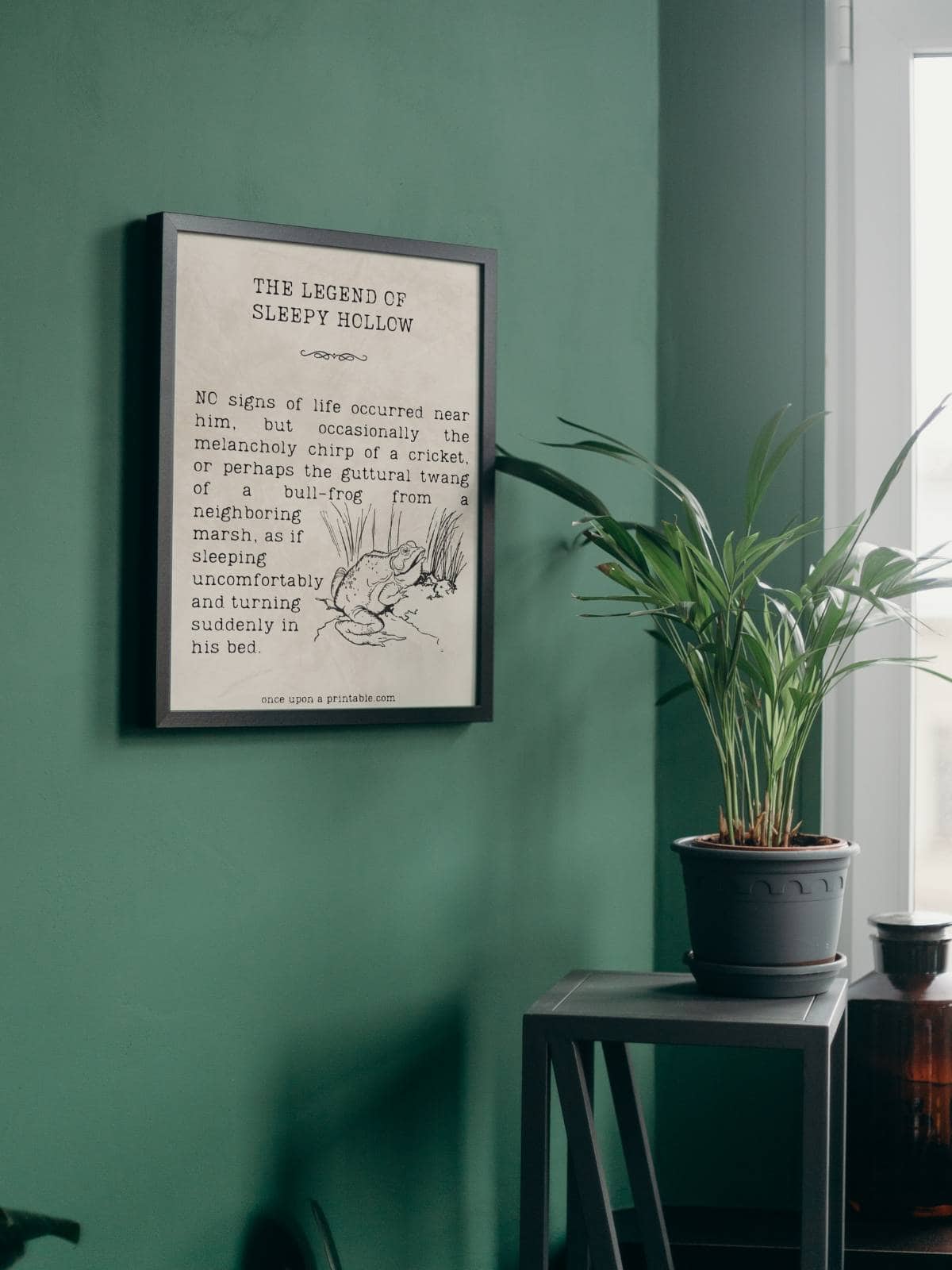 A quote from the Legend of Sleepy Hollow framed and displayed on a green wall next to a house plant.
