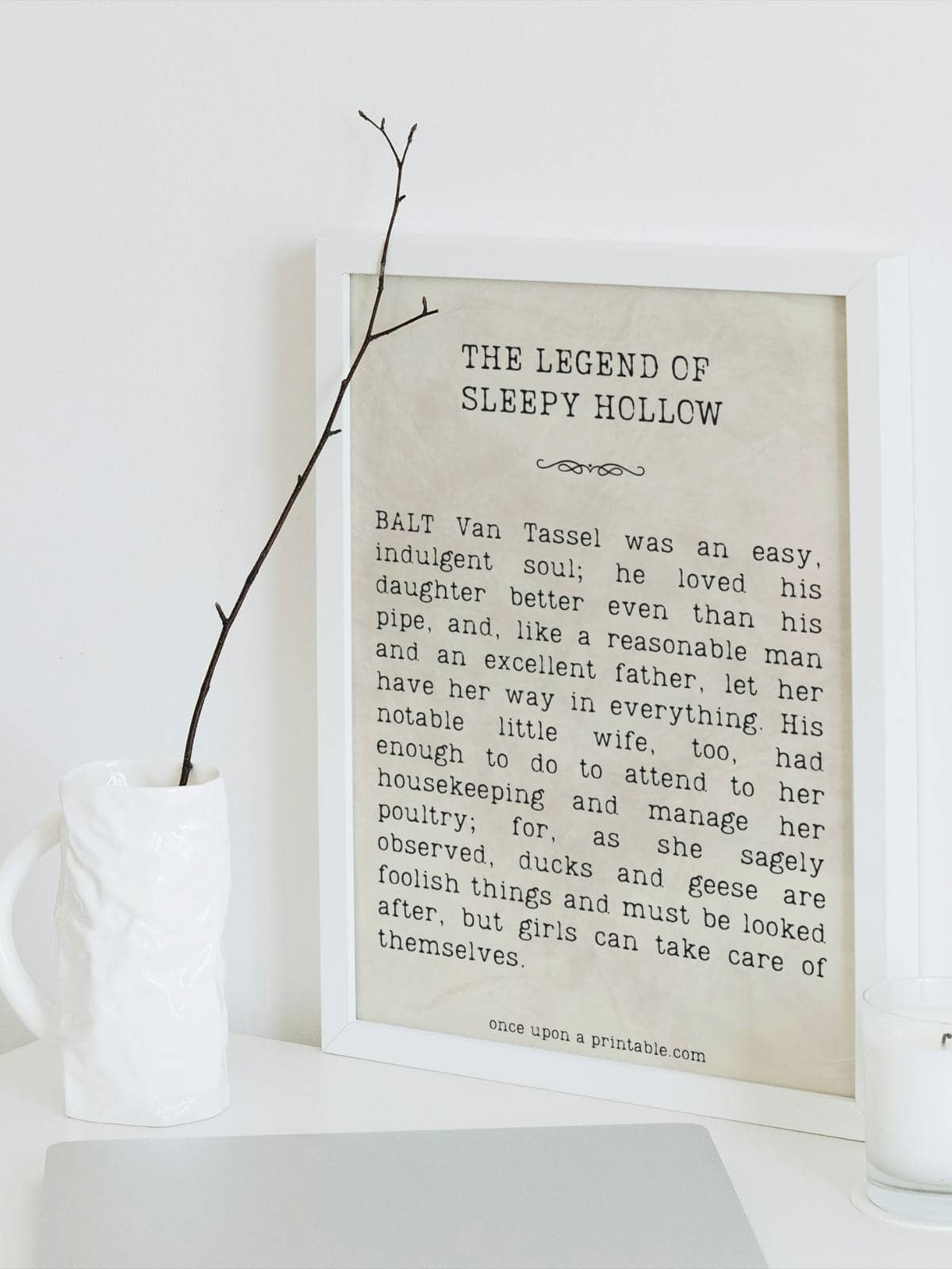 A framed quote from the book the Legend of Sleepy Hollow by Washington Irving, sitting next to a vase with a little sprig.