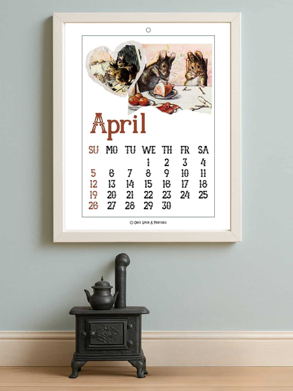 2025 calendar with "the tale of two bad mice" illustrations by beatrix potter framed and displayed on a glass side table with vase and a bowl.