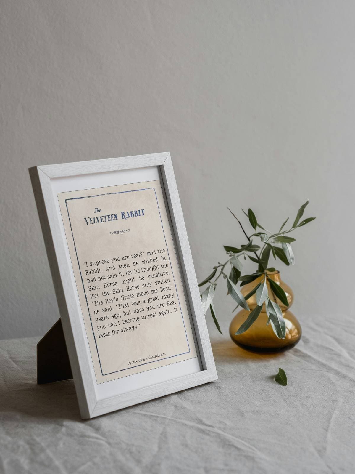 A 4x6 frame of a velveteen rabbit book quote displayed next to a small vase and twigs.