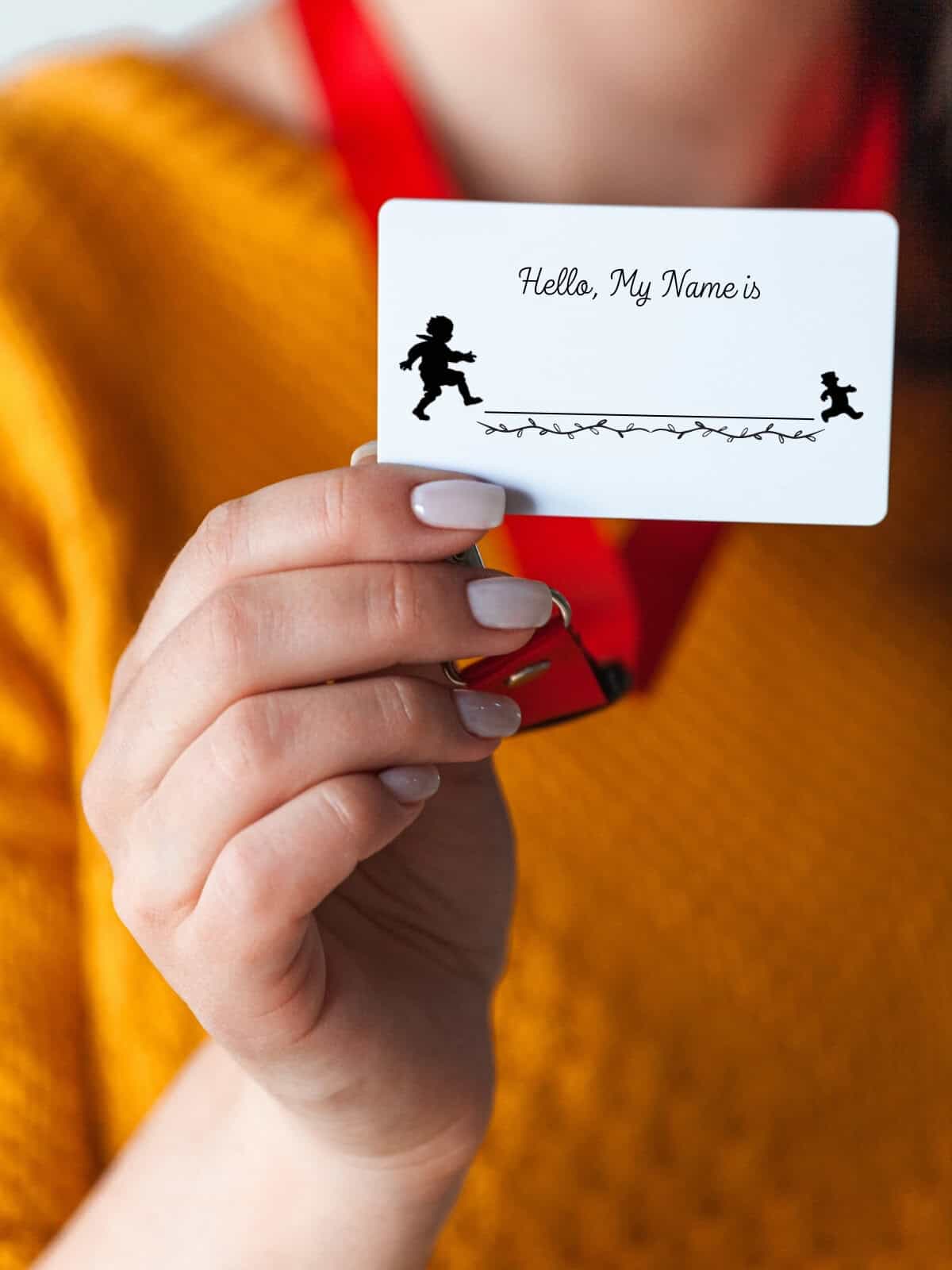A simple black and white design of a "little gingerbread man" name tag being held up by a woman's hand.