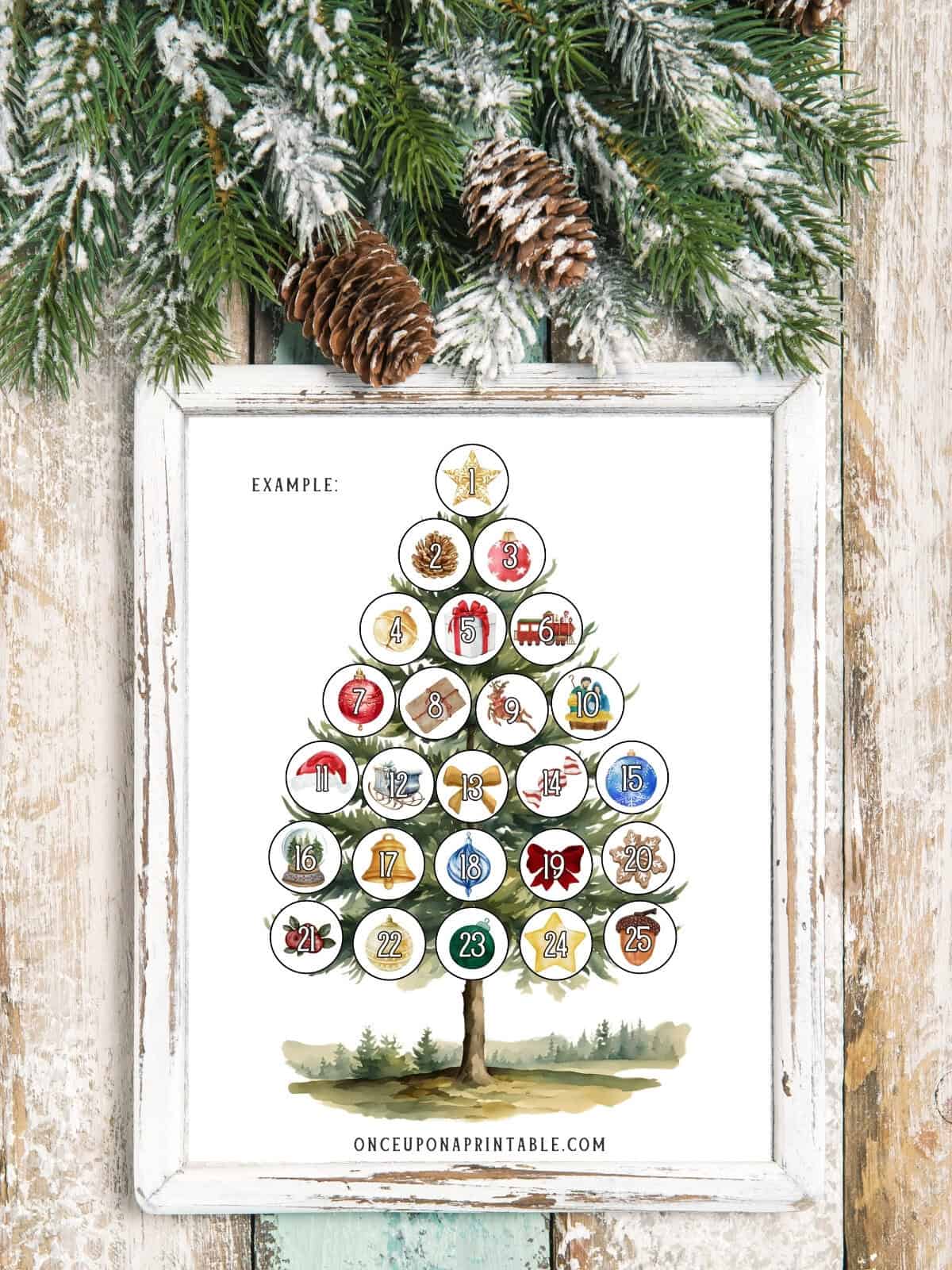 Colorful watercolor Christmas tree countdown page framed and displayed on a wooden surface with garland.