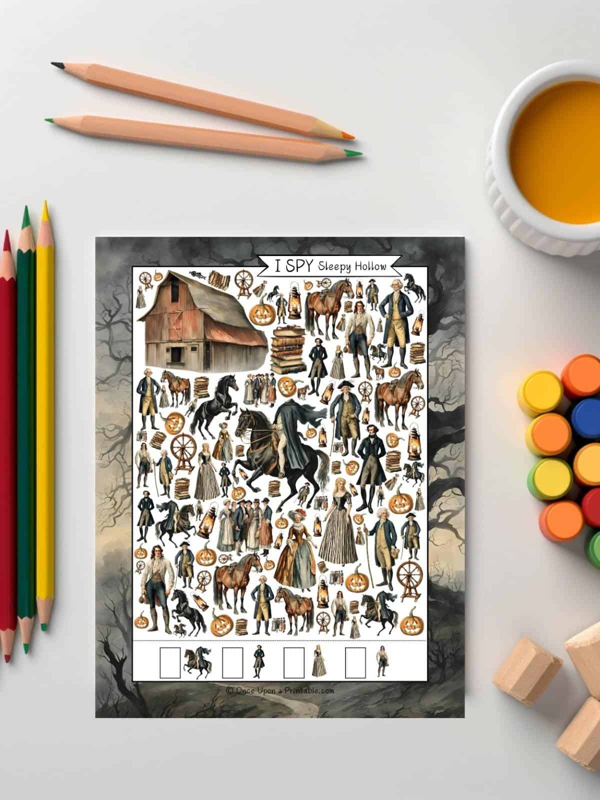 Easy version of the Sleepy Hollow I spy sitting on a white table next to some coloring pencils and paints.