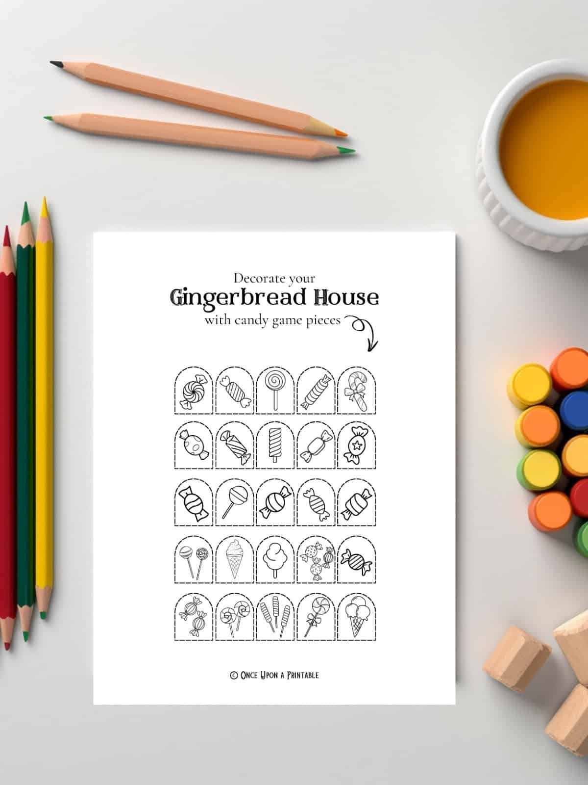 Gingerbread coloring decorations for the house printable sitting on a white table with coloring supplies like pencils and paints.