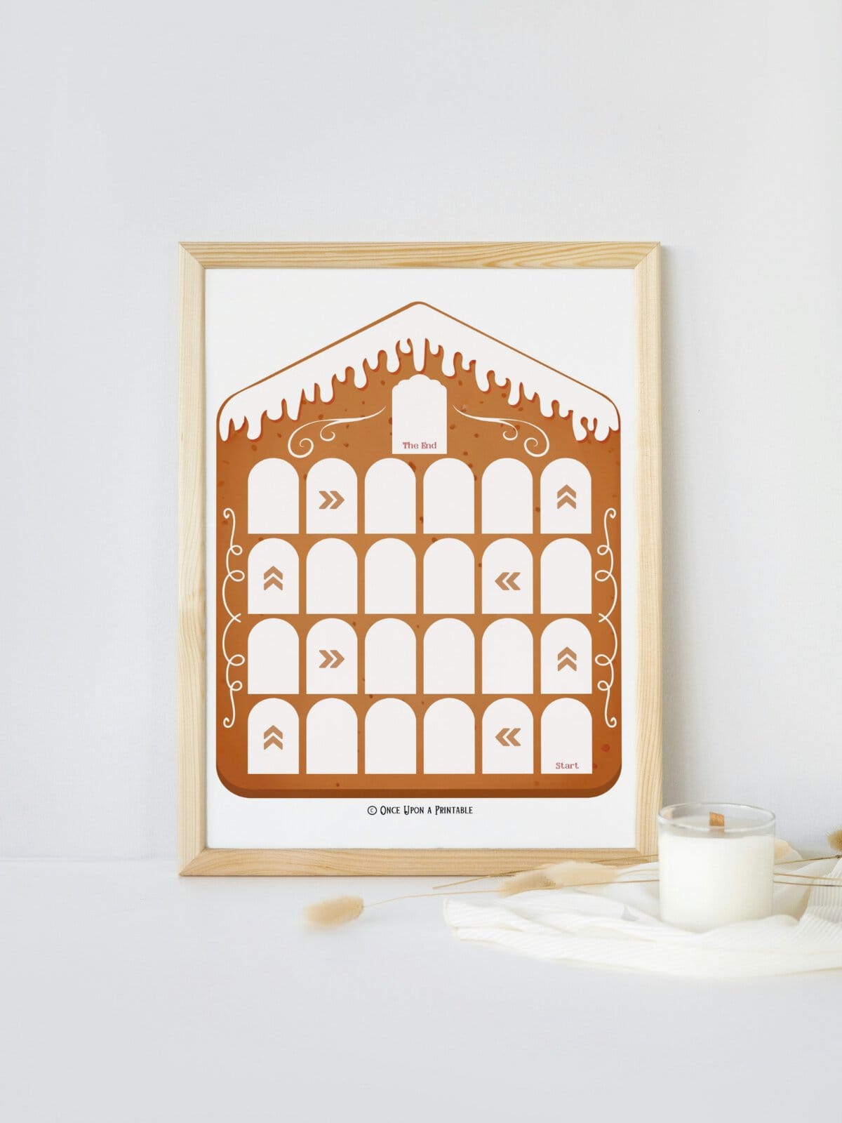 Gingerbread House Christmas countdown framed and displayed next to a candle.
