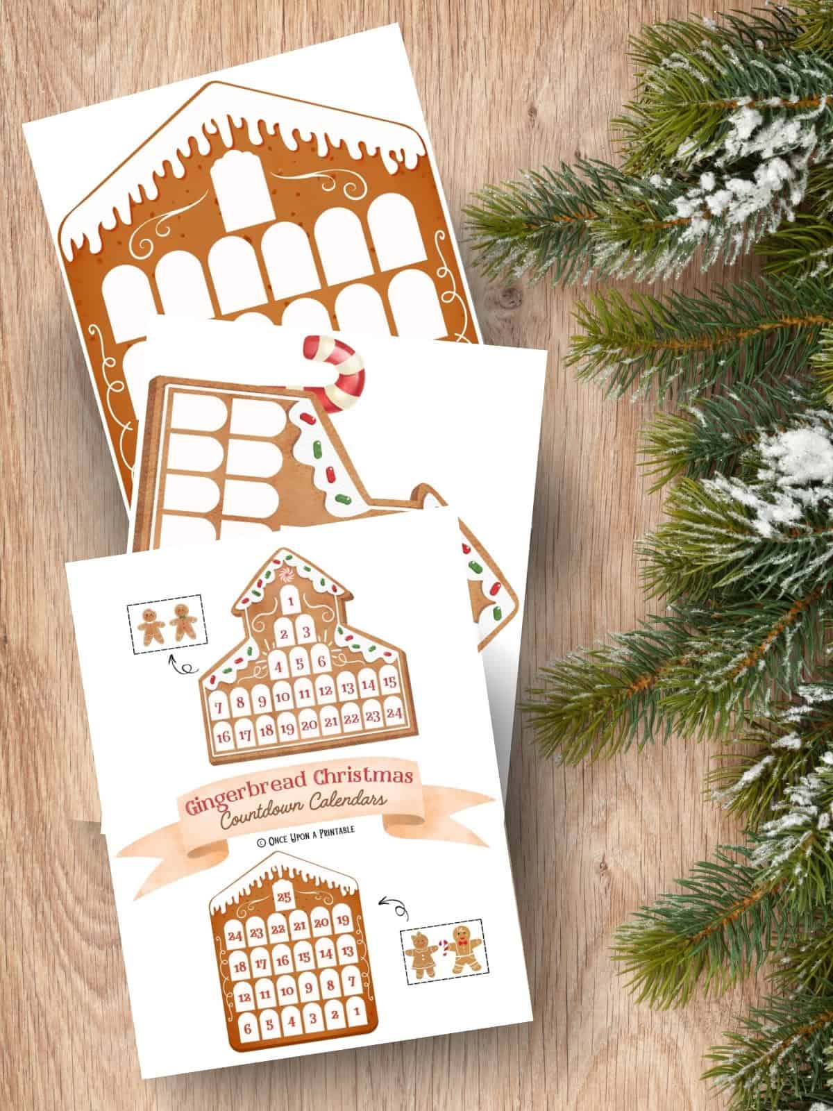 Gingerbread house Christmas countdown printables laying on a wooden table with a christmas tree garland.