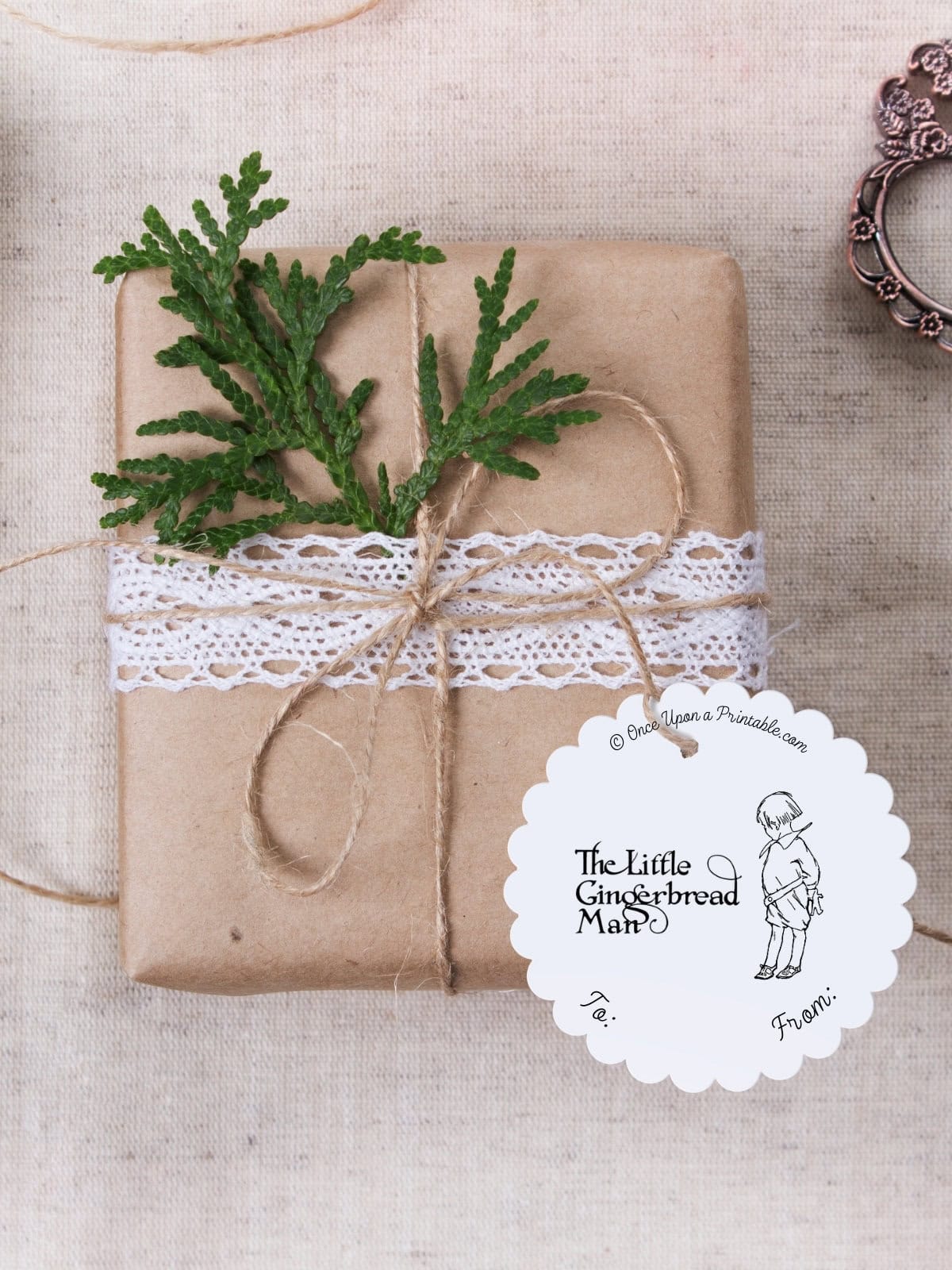 A black and white illustration from the book The little Gingerbread Man as a gift tag attached to a brown paper package with lace and a sprig of evergreen.