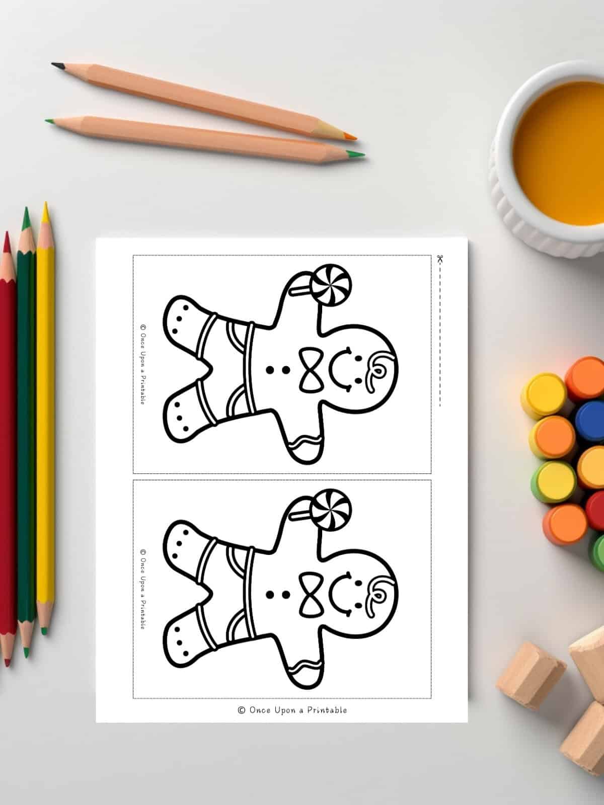 Mini Sized Gingerbread coloring pages next to coloring supplies.