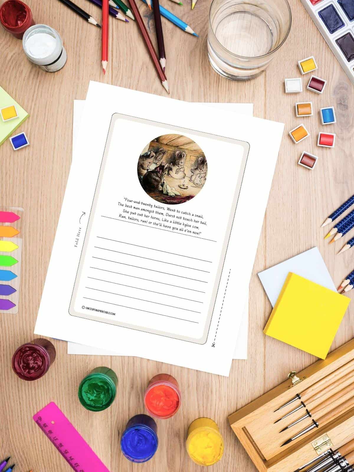 The Tailor of Gloucester stationary sitting amongst art supplies on a wooden surface.