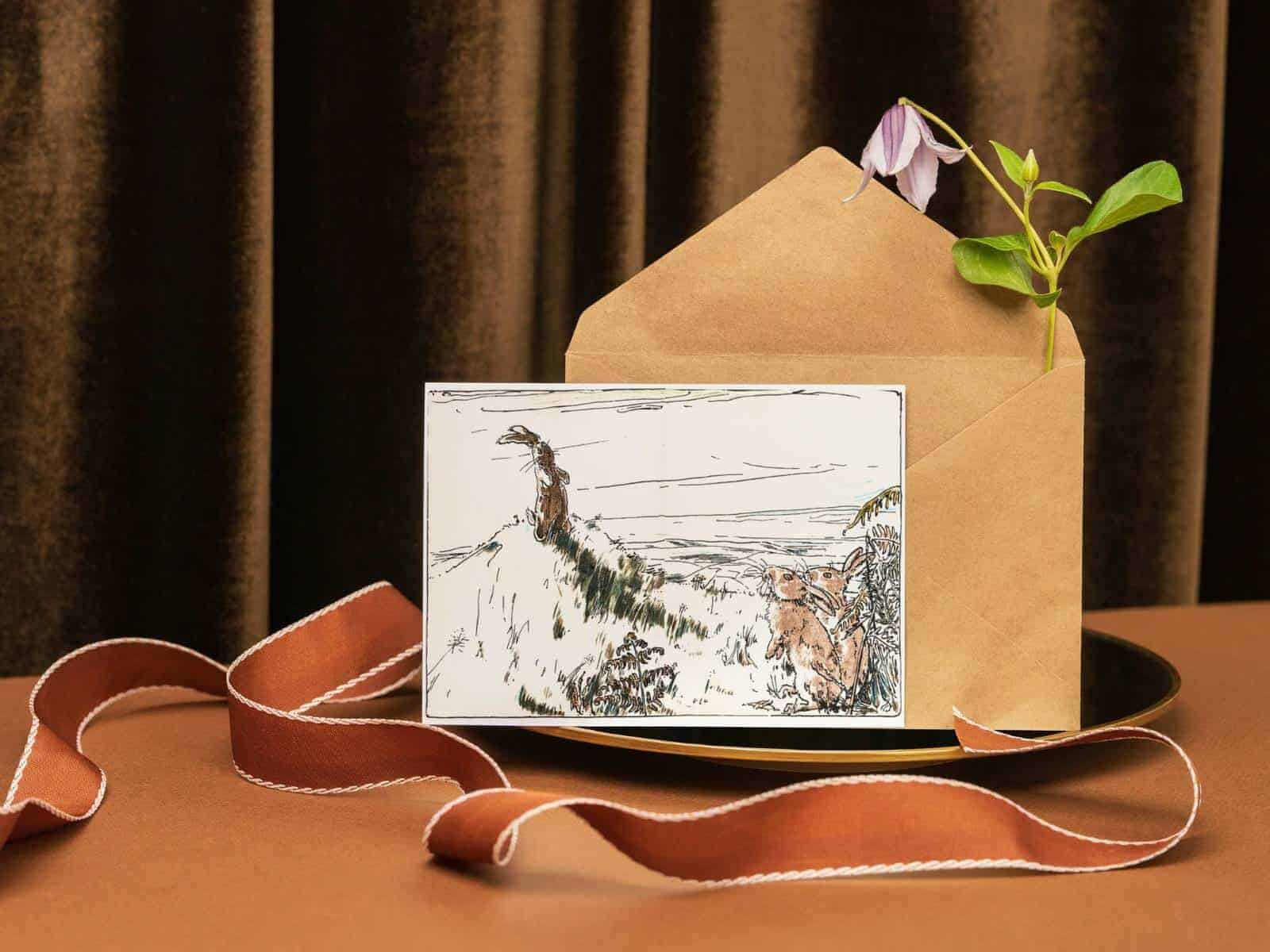 The Velveteen Rabbit note card and envelope sitting on a plate by an orange velvet ribbon.