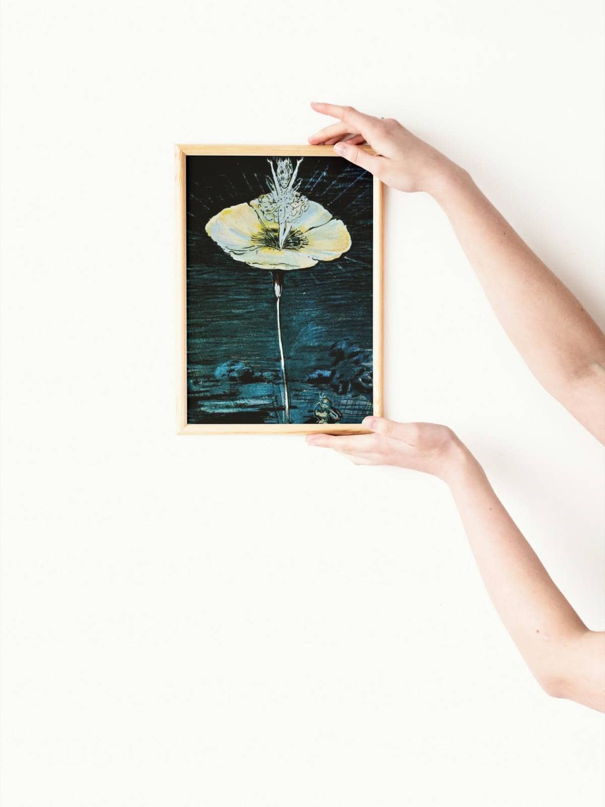 A framed art print of the Velveteen rabbit and the flower fairy being held up by two women's arms.