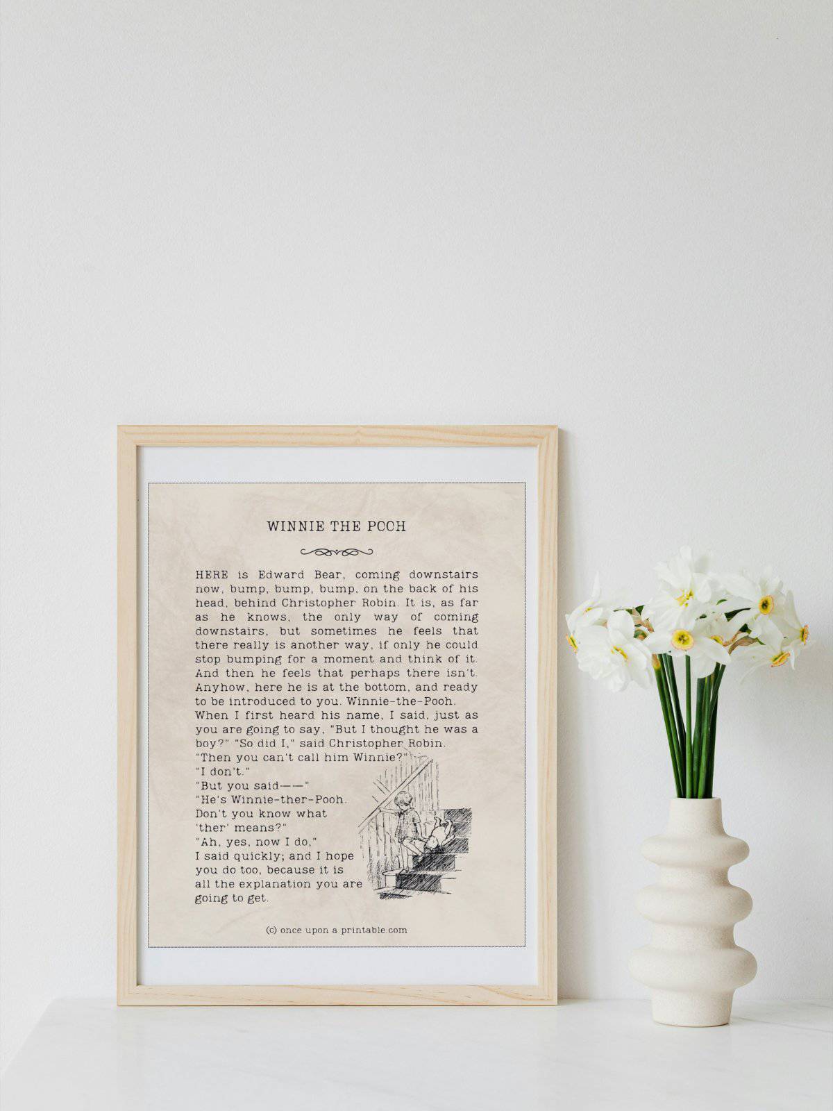 Winnie the Pooh illustration and book excerpt framed and displayed next to a vase with white daffodils.