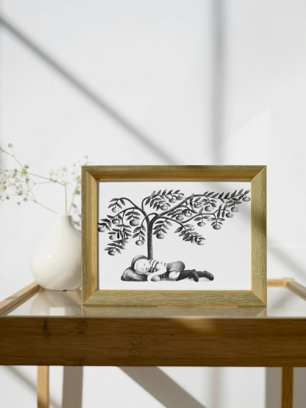 Framed illustration of Elmer sleeping under a tree, from the book my father's dragon, sitting on a glass side table.