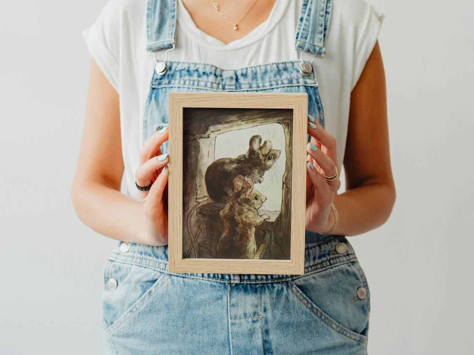 Two fat little mouse in watercolor illustrated by Beatrix potter held in the arms of a woman wearing blue denim overalls.