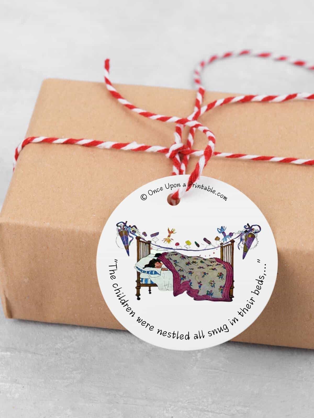 Vintage illustrated "twas the night before christmas" by jessie willcox smith gift tag on a brown paper wrapped gift.