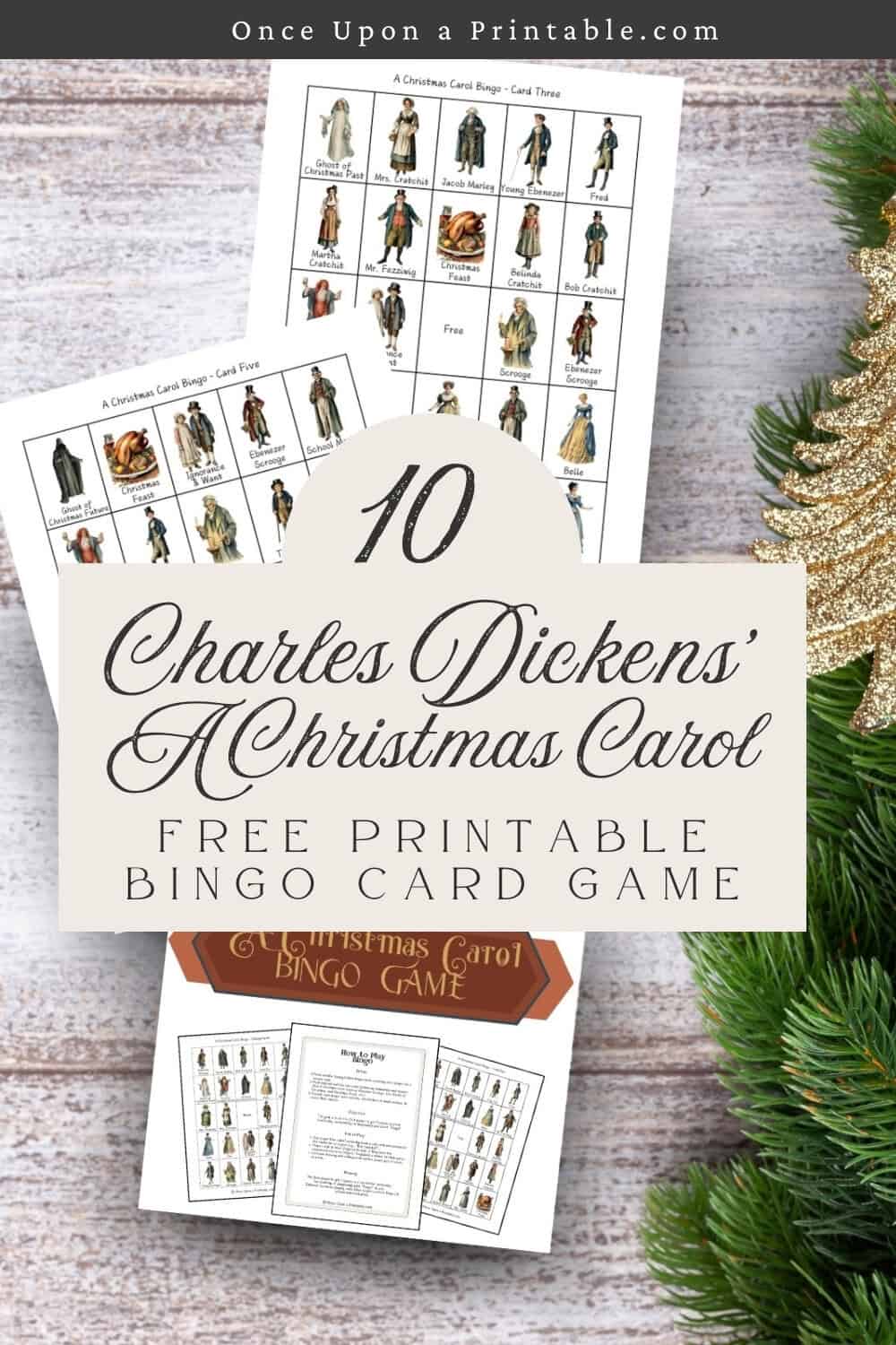 A charles dickens inspired "a christmas carol" bingo game printables laying on a wooden surface with green garland.