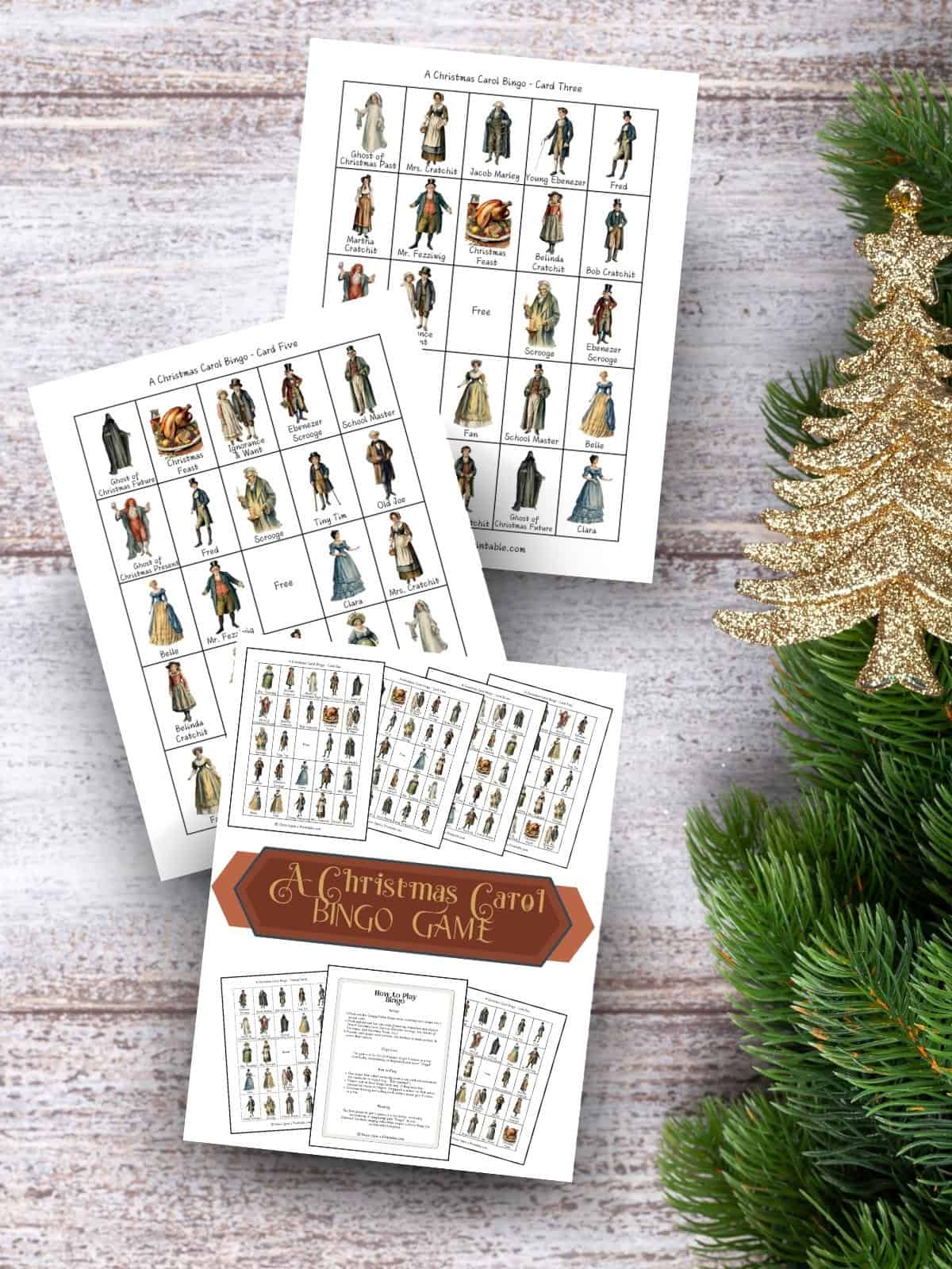 A charles dickens inspired "a christmas carol" bingo game printables laying on a wooden surface with green garland.