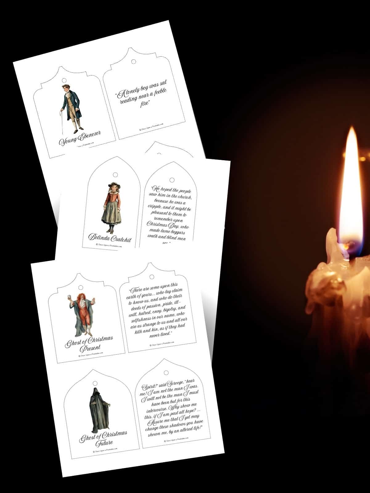 A Christmas Carol Christmas tree ornament pages laying on a dark background by a candle that is lit.