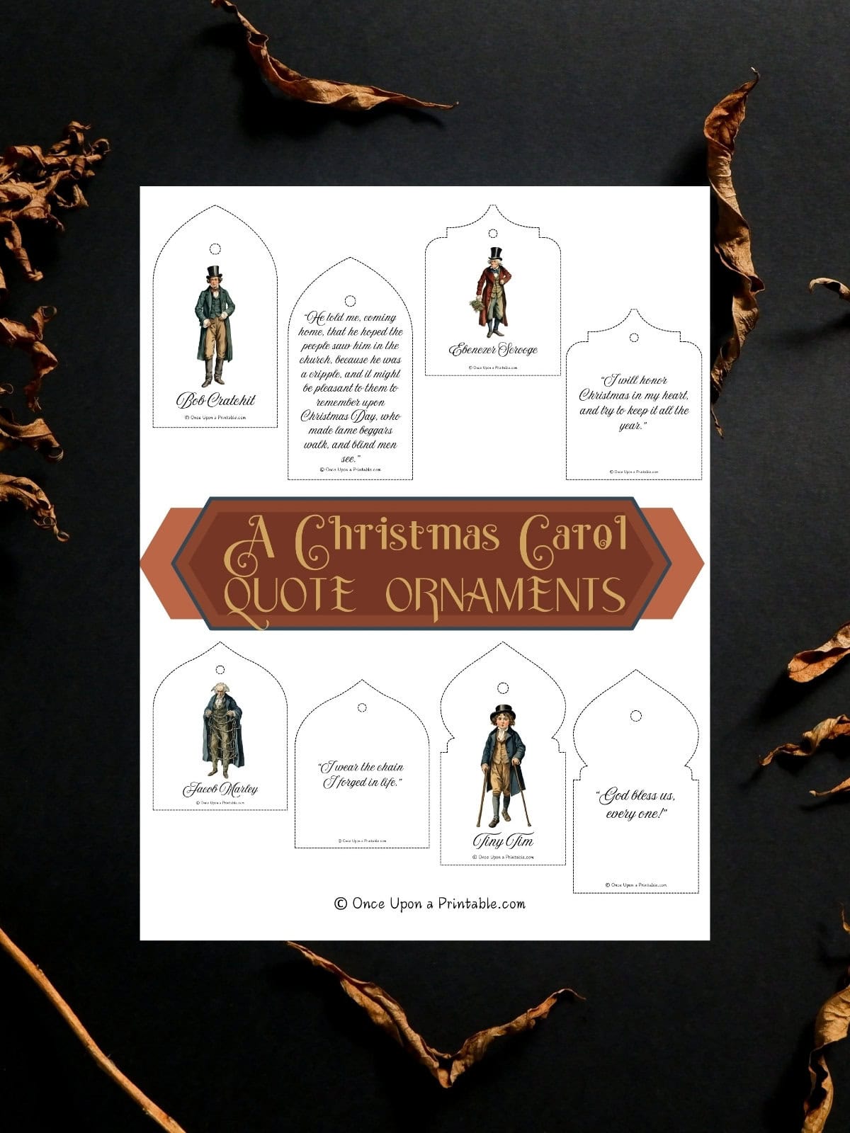 A Christmas Carol by Charles Dickens quotes and watercolor graphics of characters from the story as Christmas tree ornaments printed out and laying on a dark background with fall leaves.