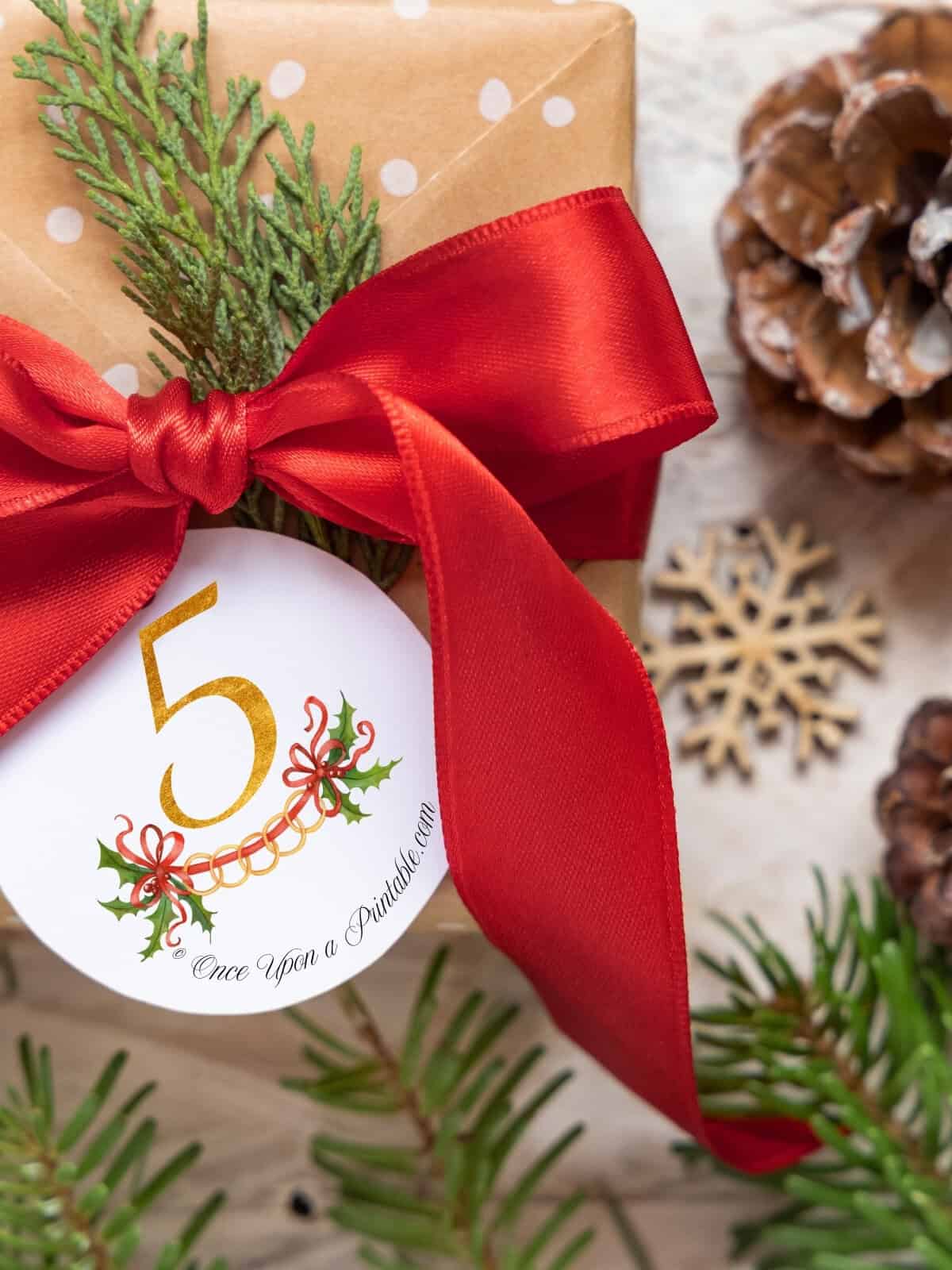 Five golden rings gift tag on a christmas present wrapped with a big satin red ribbon.