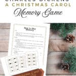 how to play instructions for the memory game that is A christmas carol themed, printed, and displayed on a wooden background with garland and pinecones.