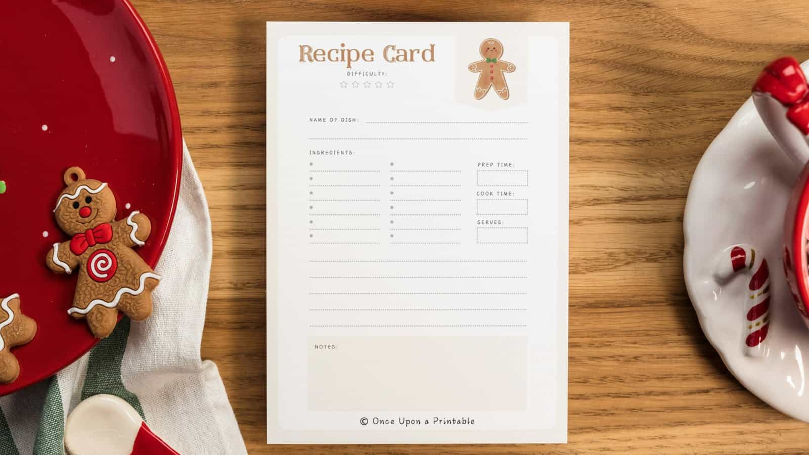 Gingerbread Man recipe card laying on a wooden table next to red plates and a gingerbread man ornament.