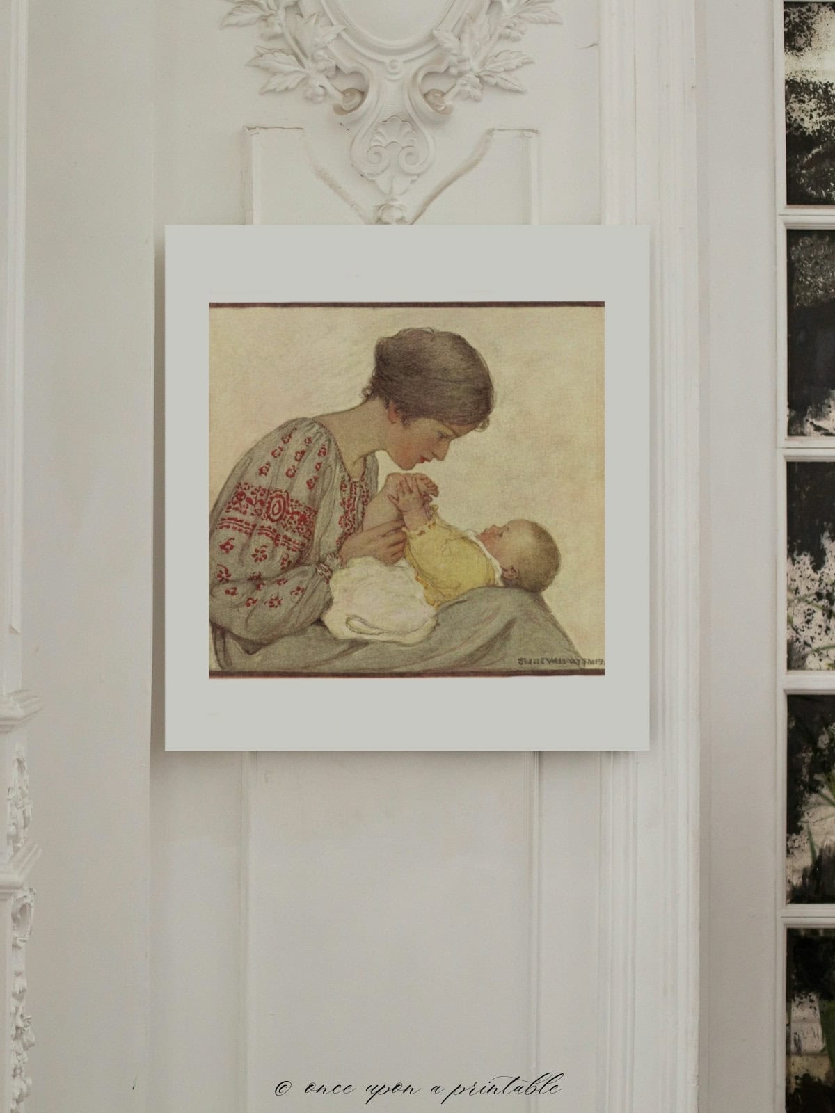 A framed illustration of a mother holding her baby hung on a wall.