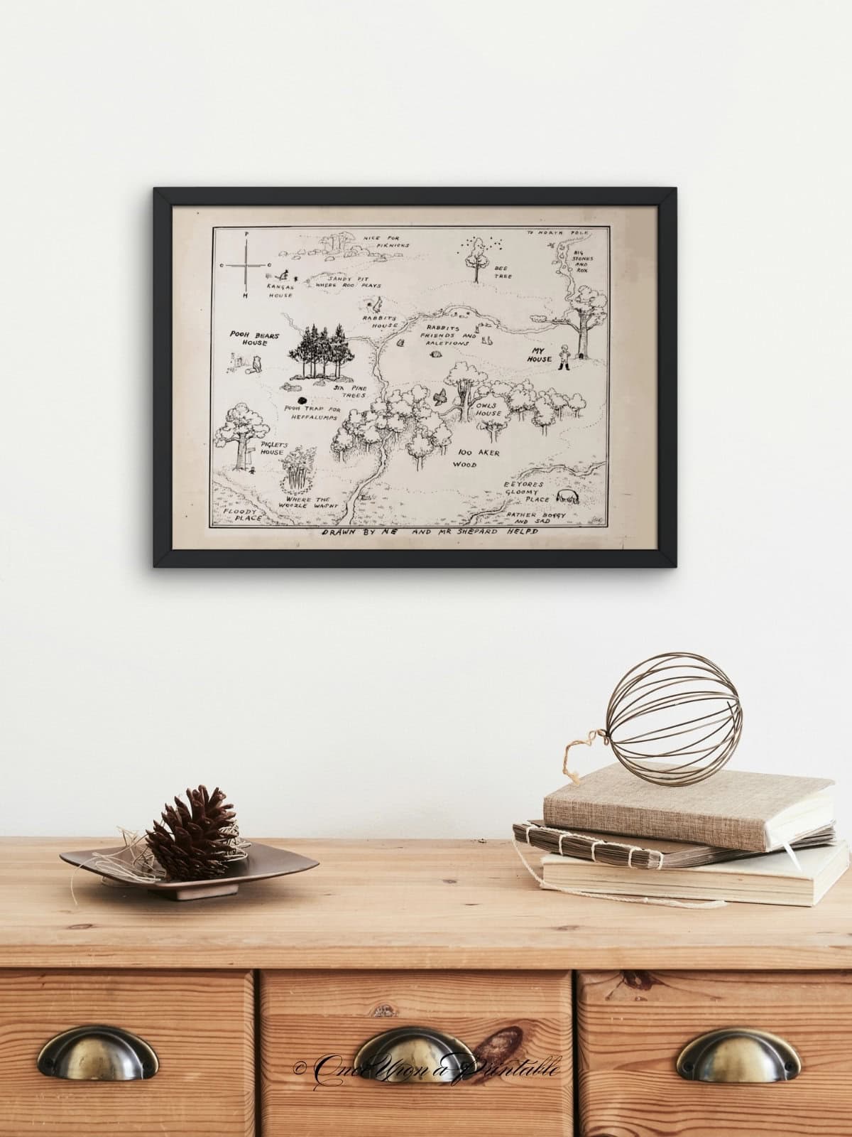 A. A. Milne's winnie the pooh map of the hundred acre wood by E. H. Shepard framed and displayed above a dresser. 