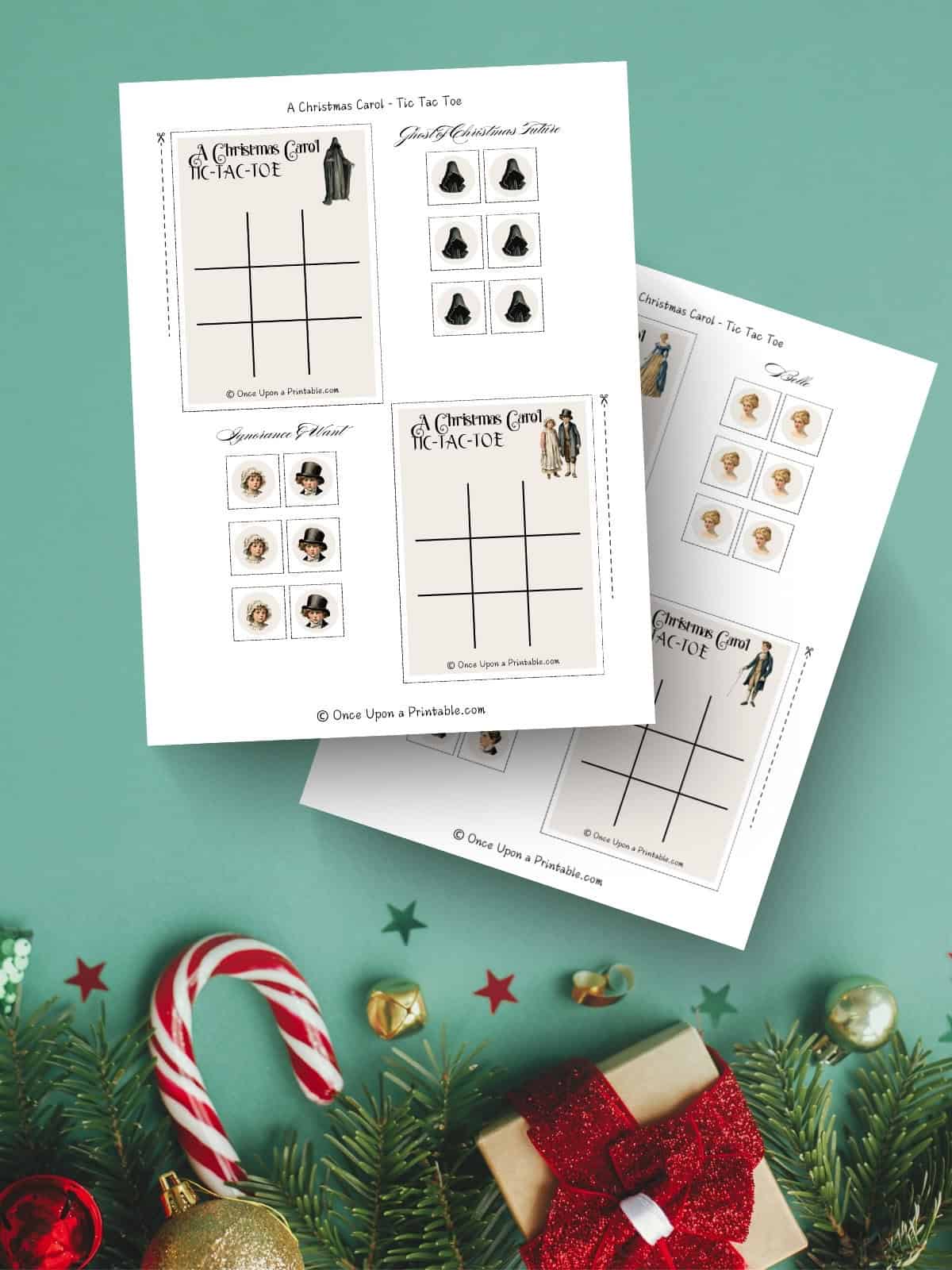 A Christmas Carol illustrated tic tac toe cards and character tokens laying on a green background with christmas tree ornaments.