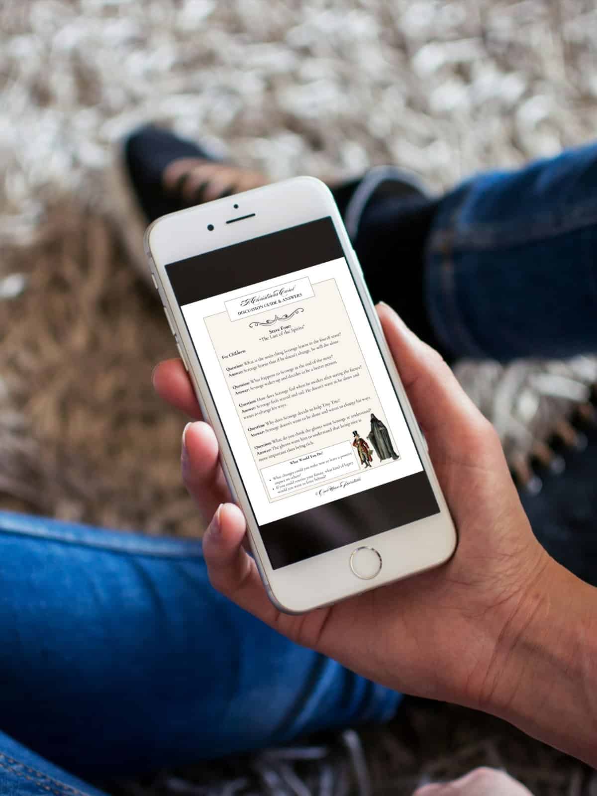 A Christmas Carol by charles dickens discussion guide on a mobile phone held in a man's hand.