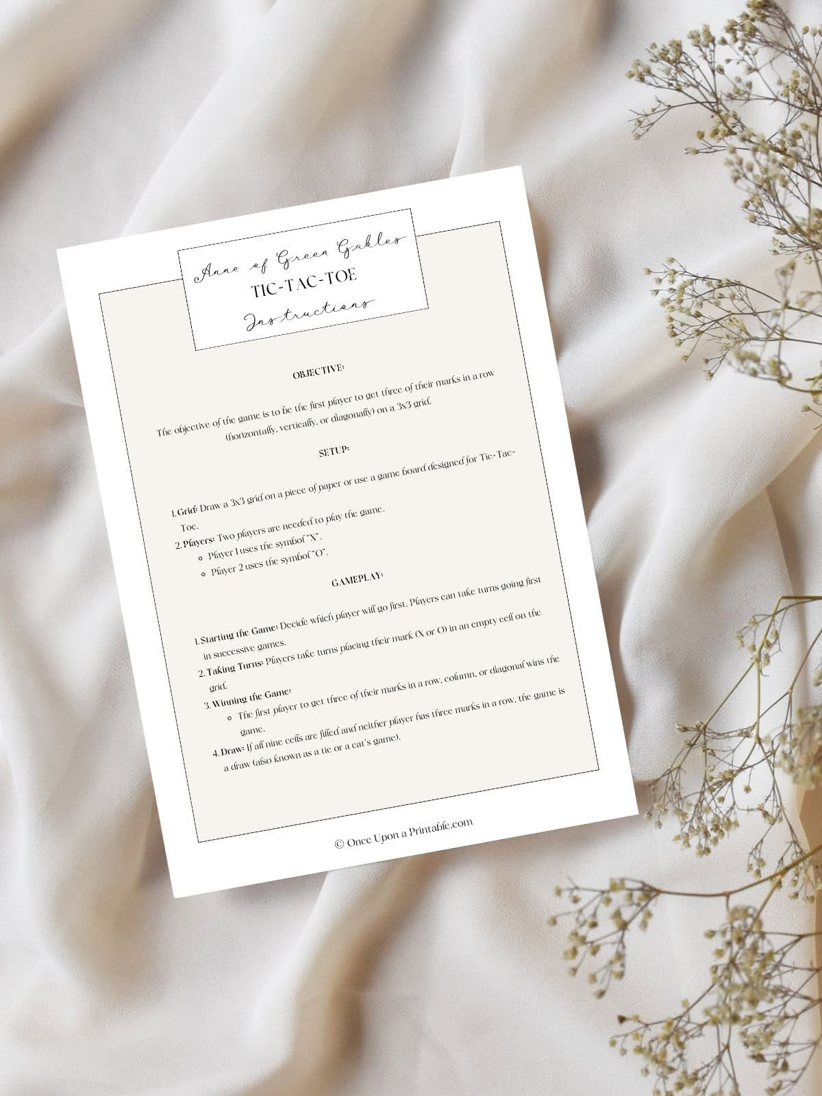 Anne of green gables tic tac toe instructions page laying on a creamy table cloth with baby's breath flowers. 