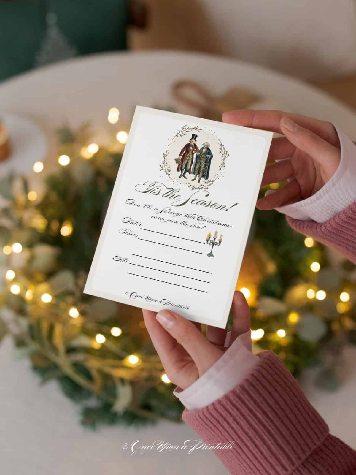 A Christmas Carol inspired party invitation held by a woman's hand.