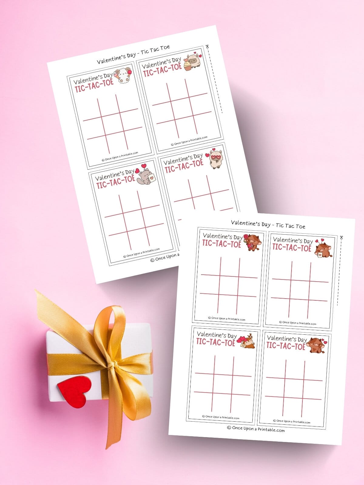 Cute graphic valentine's day tic tac toe cards sitting on a pink background with a wrapped gift.