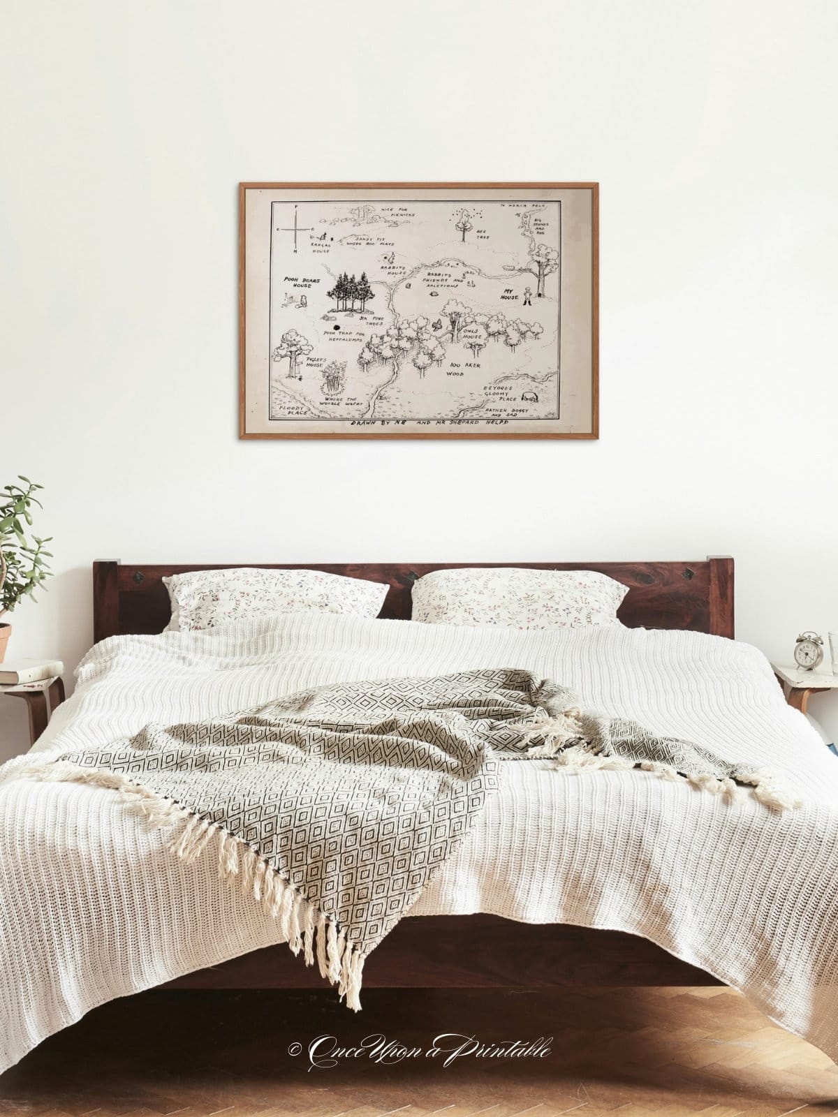 E. H. Shepard's 100 acre wood map framed and hanging above a bed in a bedroom.