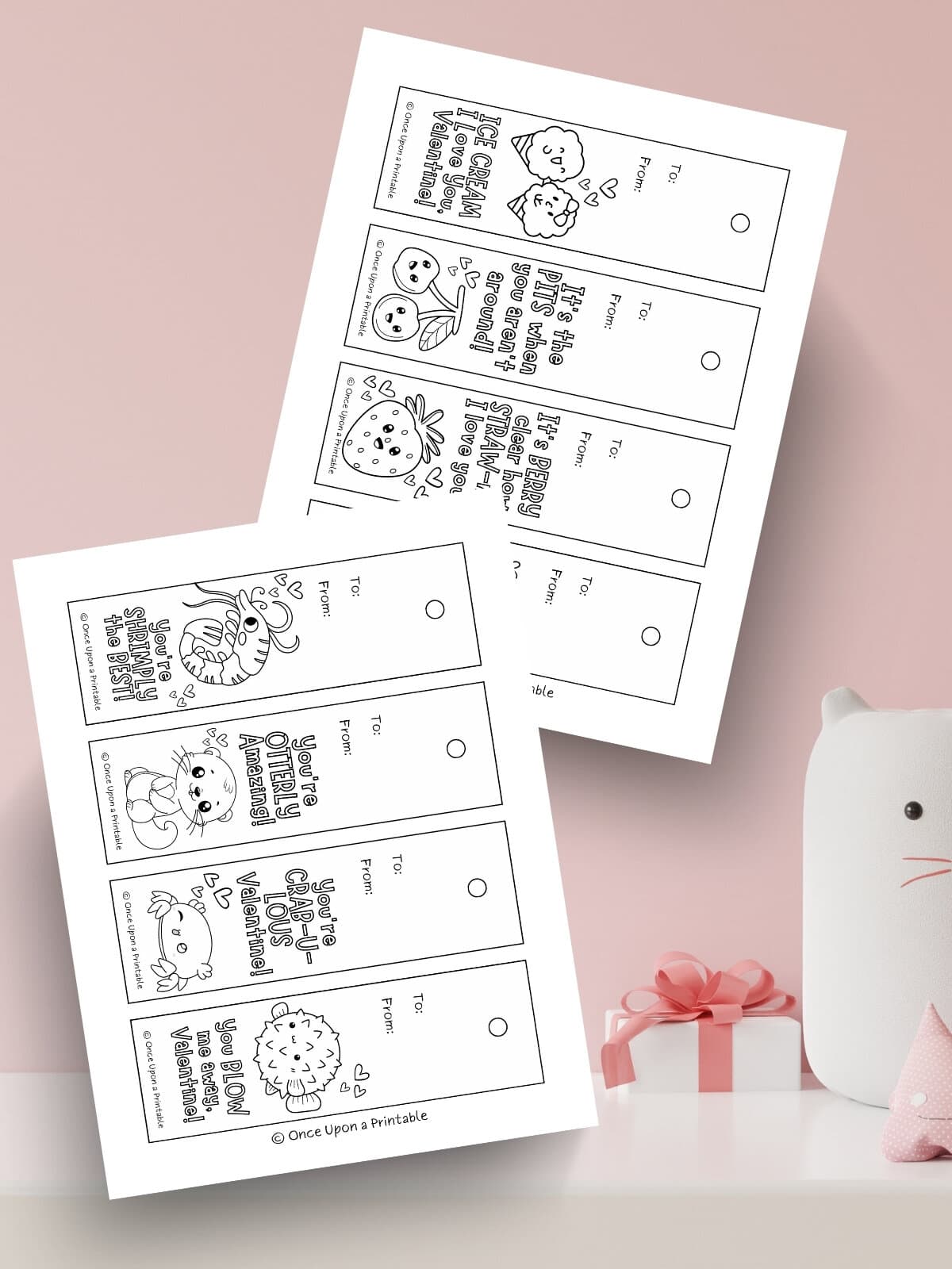 Fun coloring bookmarks for valentine's day laying on a pink background.