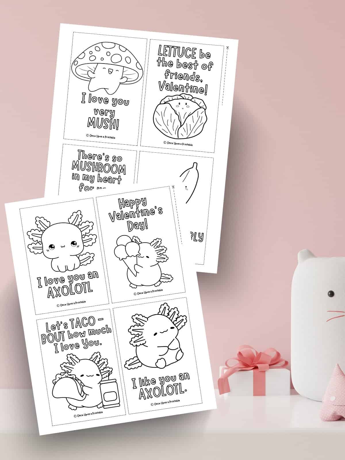 Mushroom and Axolotl Valentine's day Coloring cards laying on a pink background.