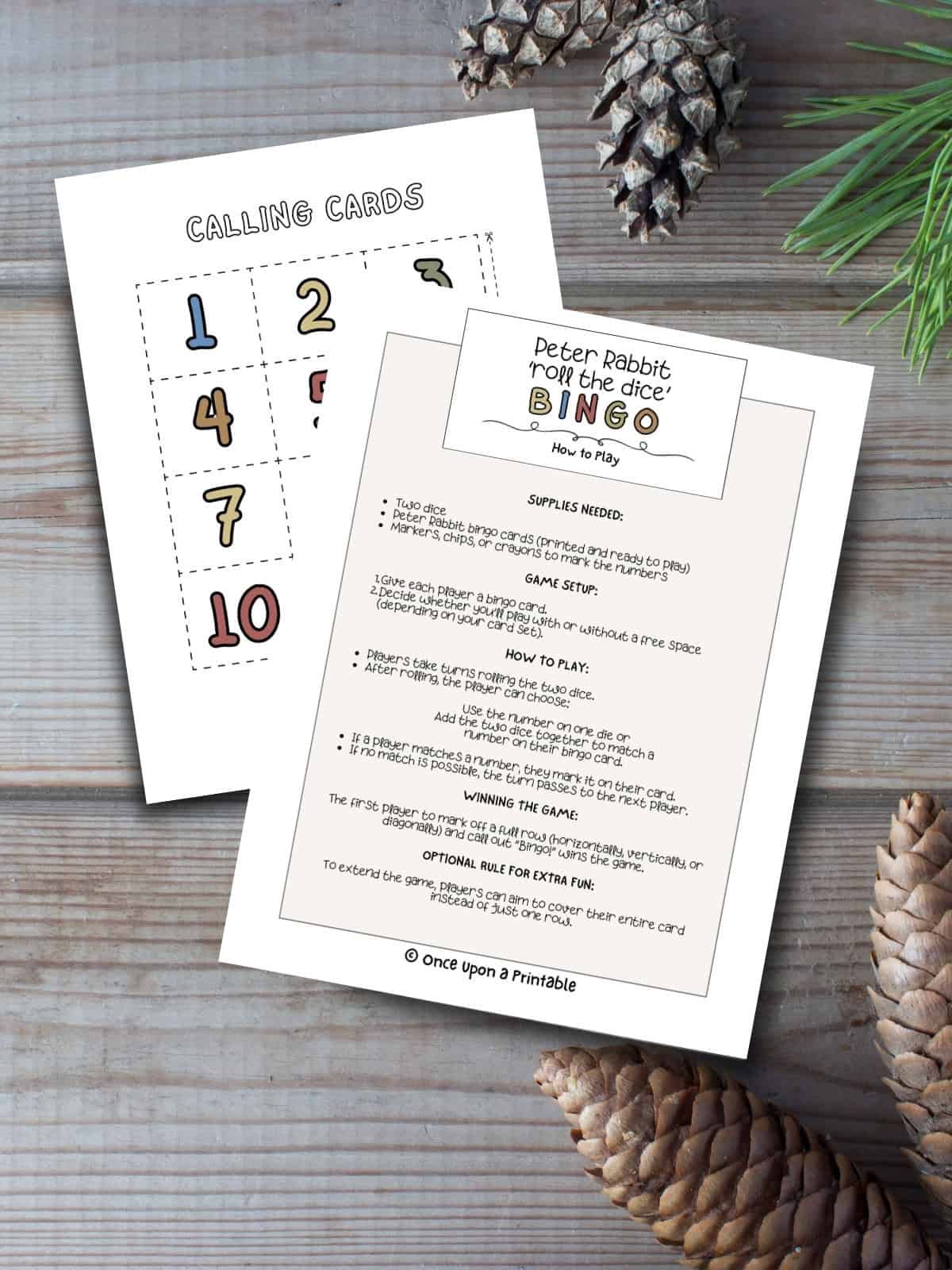 how to play the peter rabbit roll the dice bingo game with colorful call out cards laying on a wooden floor with pinecones.