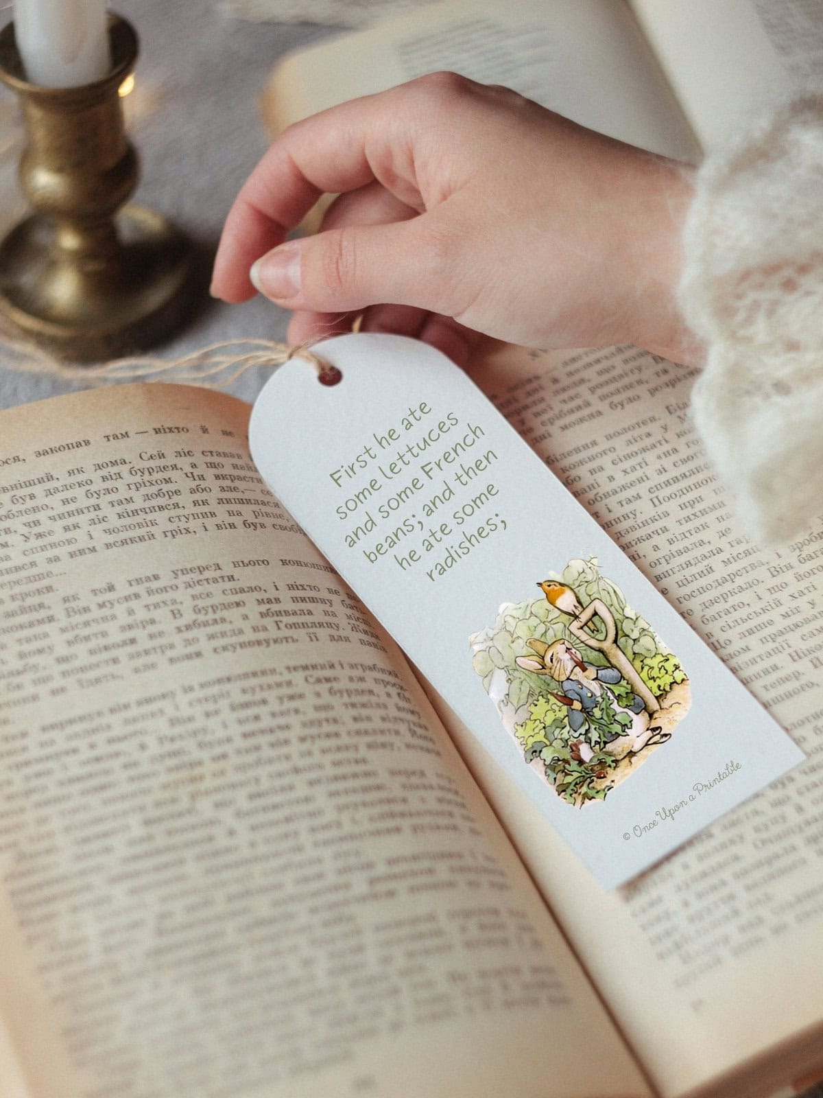 The Tale of Peter Rabbit story book mark being held by a woman in a book.