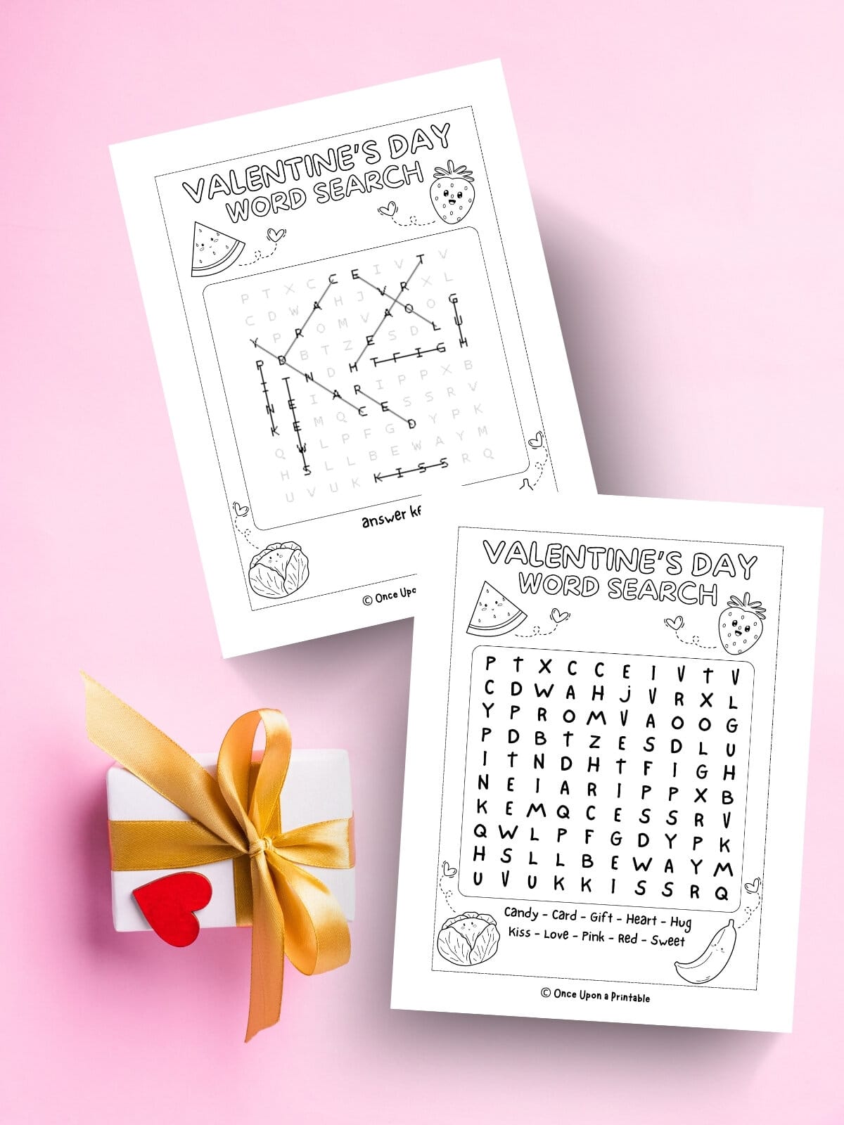 A Fruit themed valentine's day crossword puzzle and answer key laying on a pink background with a gift.