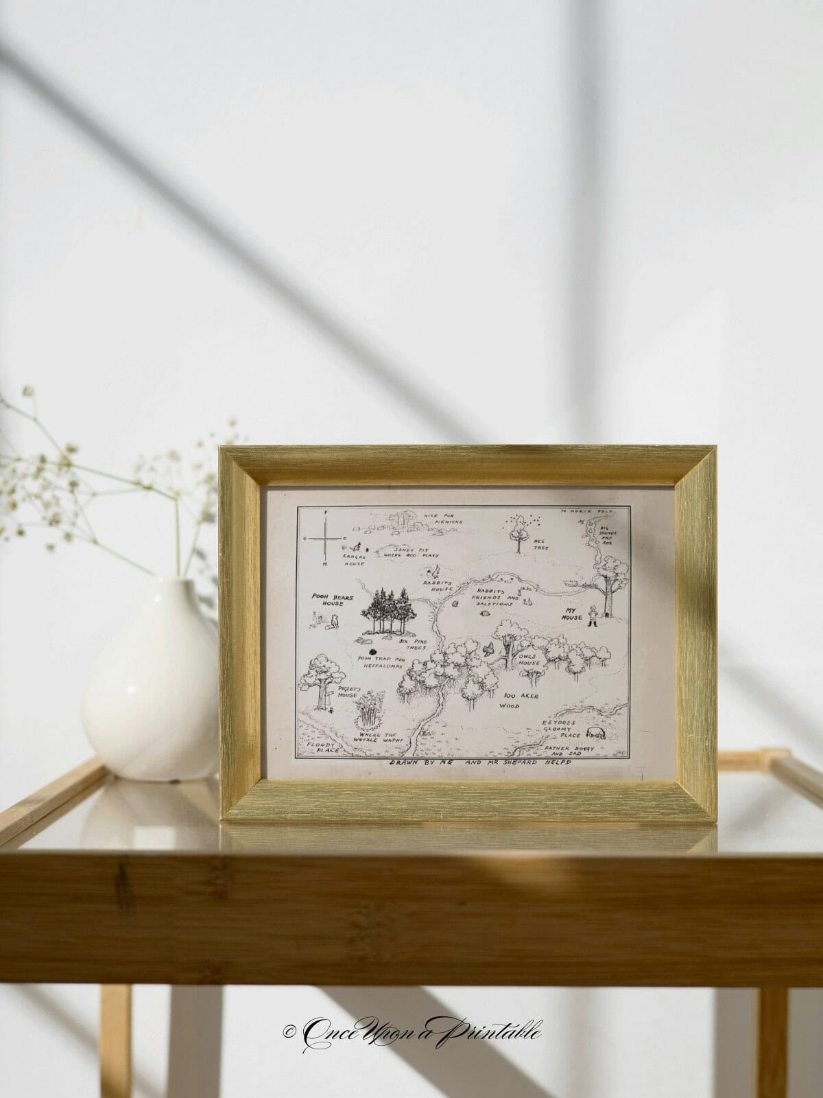 E. H. Shepard classic hundred acre wood map framed and sitting on a side table.