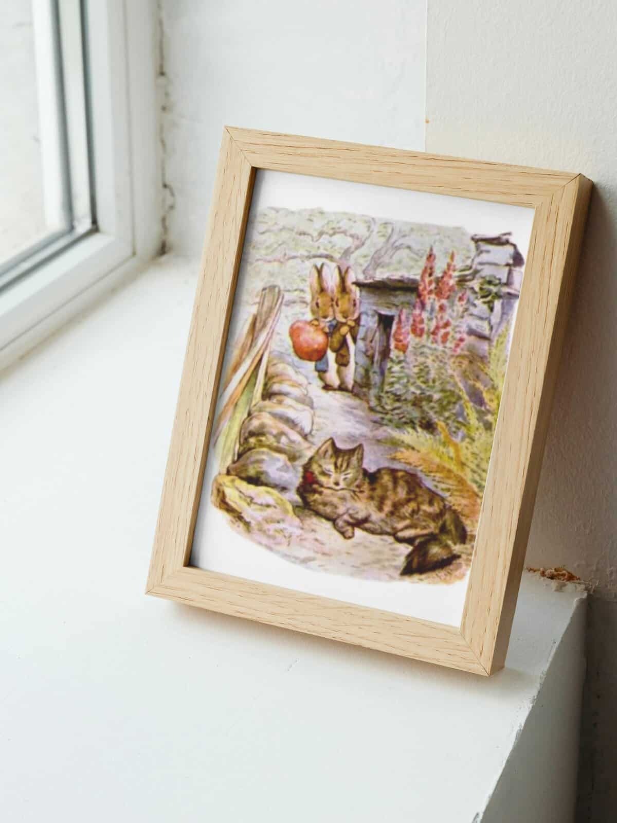 Benjamin Bunny images by Beatrix Potter framed and sitting on a window sill.