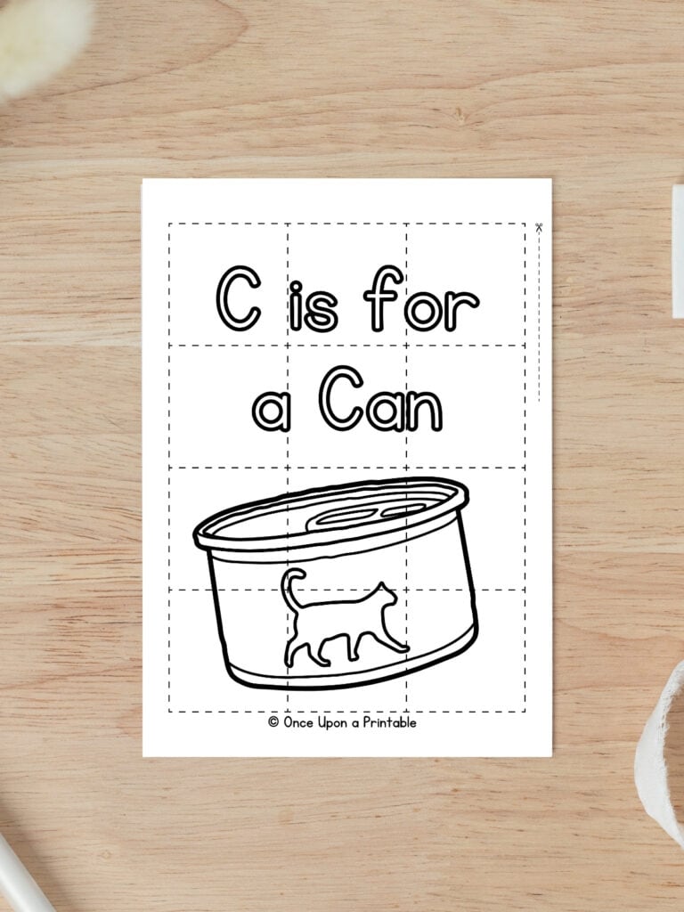 C is for Can coloring puzzle activity worksheet laying on a wooden table.