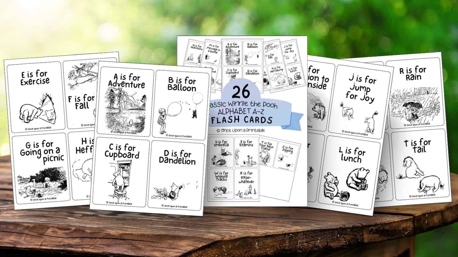 Classic winnie the pooh flash cards for the alphabet, printables laying on a wooden table outside.